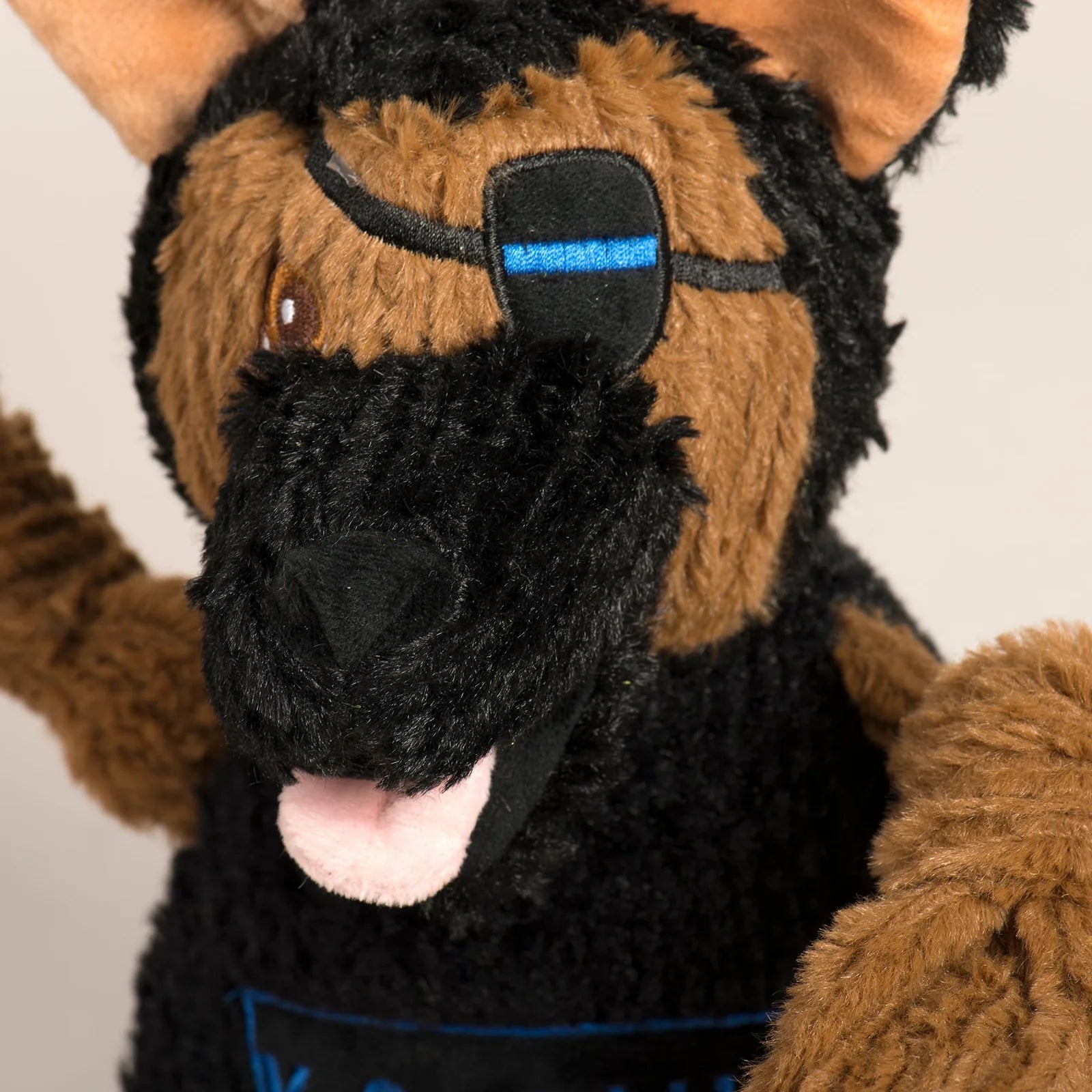 Plush K-9 Chief dog toy in black and brown, featuring knotted limbs and a stitched blue harness for interactive play.
