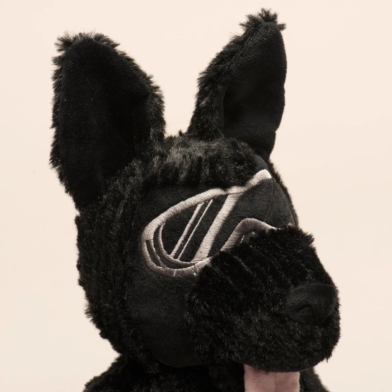 Black plush dog toy resembling a German Shepherd, featuring embroidered goggles and textured fur, perfect for interactive...