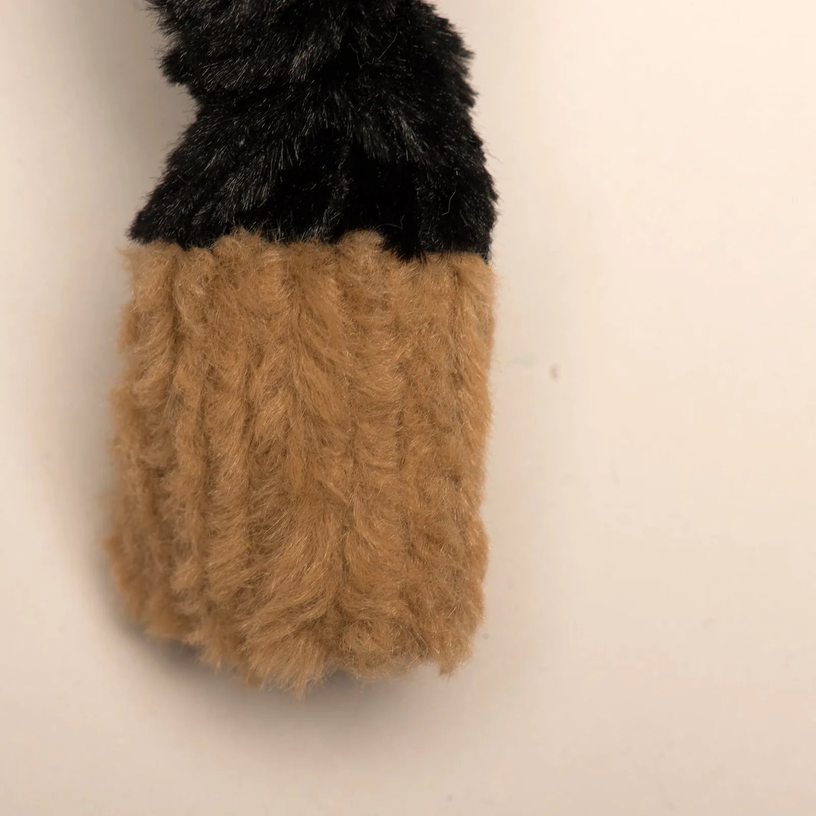 Large plush dog toy with a black and tan knotted design, ideal for heavy chewers and interactive play.