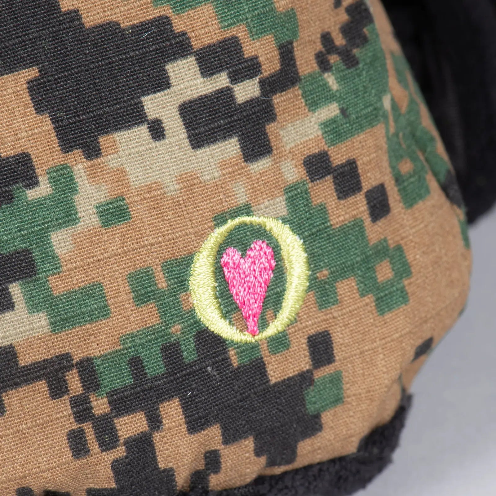 Camo-patterned plush toy with a pink heart logo, highlighting the durable design of the HuggleCause Black Lab toy.