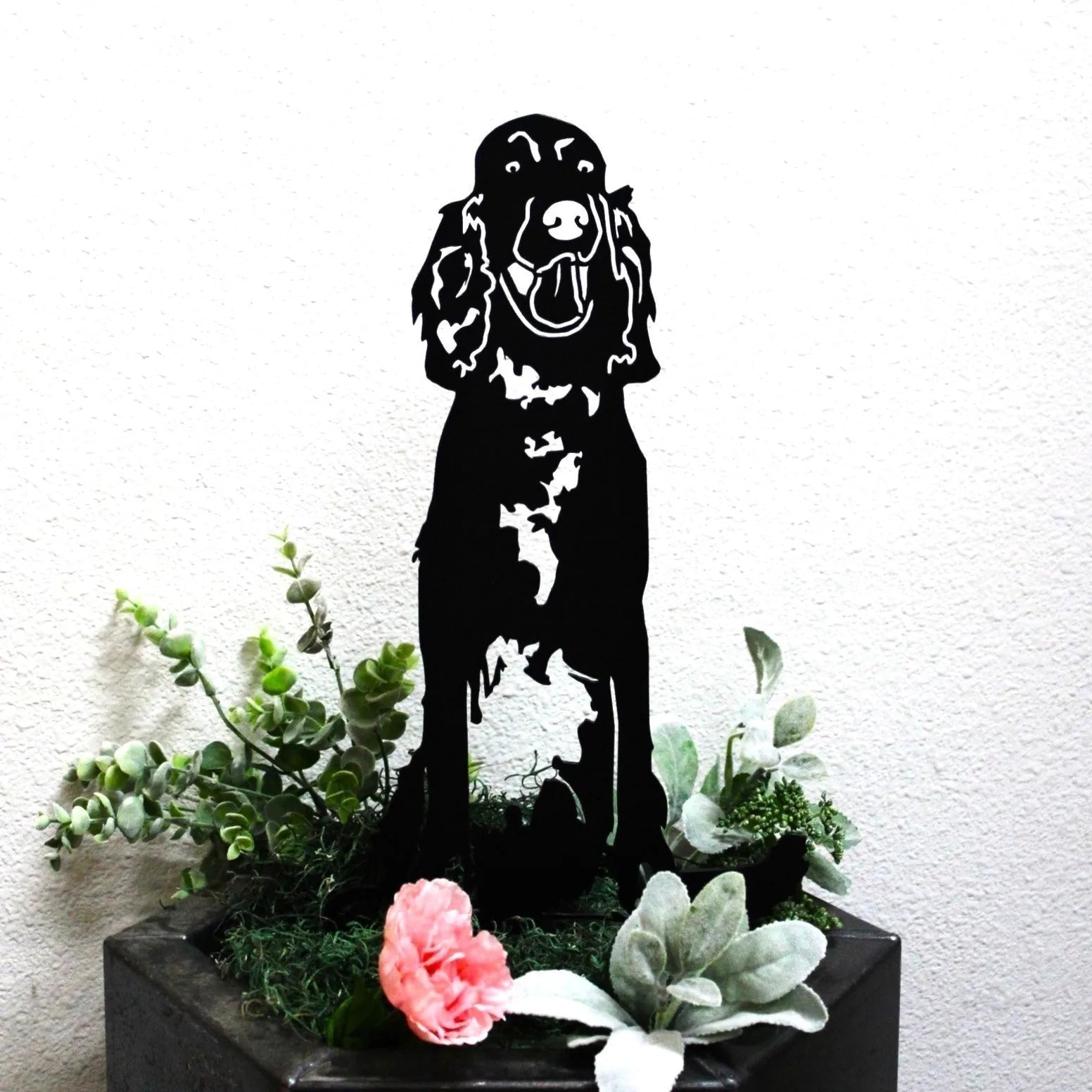 Black Irish Setter metal silhouette art placed among greenery and pink flowers, perfect for outdoor decor.