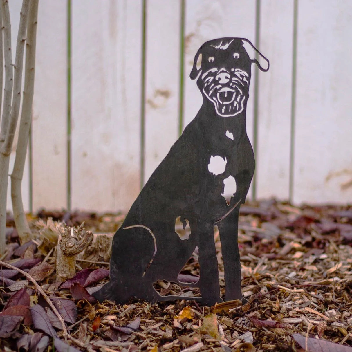 Irish Wolfhound metal silhouette in black, sitting among leaves, showcasing detailed cutouts of the dog’s features.