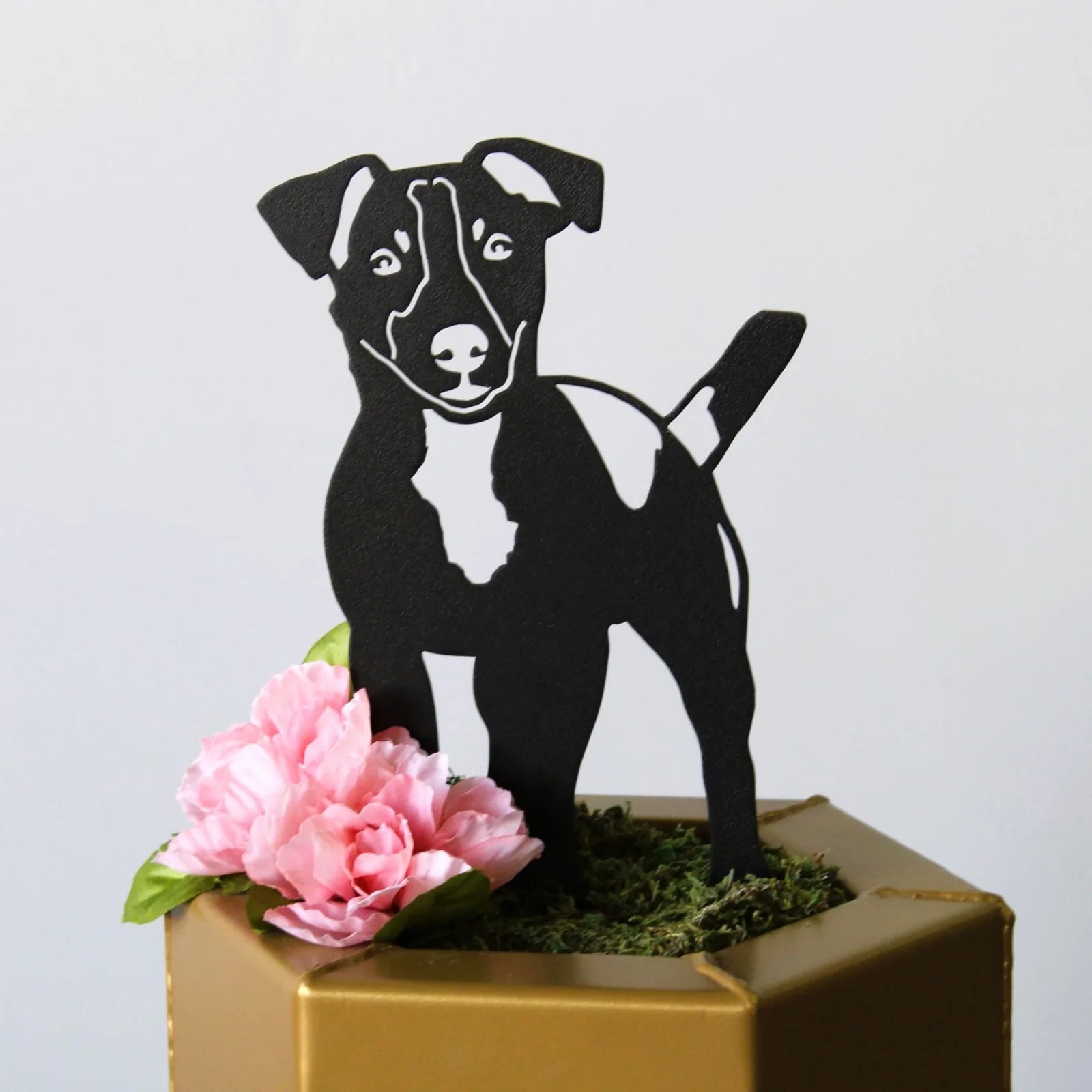 Black metal silhouette of a Jack Russell Terrier, adorned with pink flowers, showcasing outdoor dog decor.