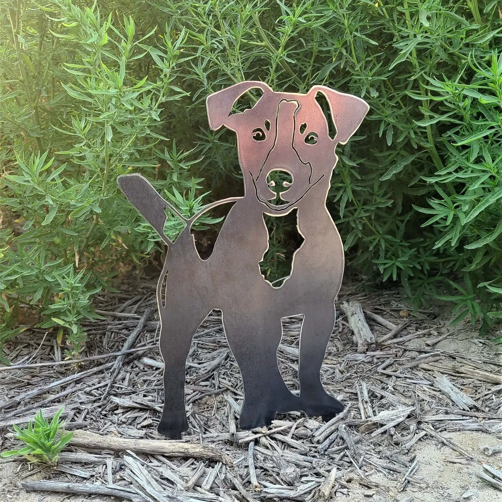 Jack Russell Terrier metal silhouette in Corten steel, standing among greenery, perfect for outdoor decor.