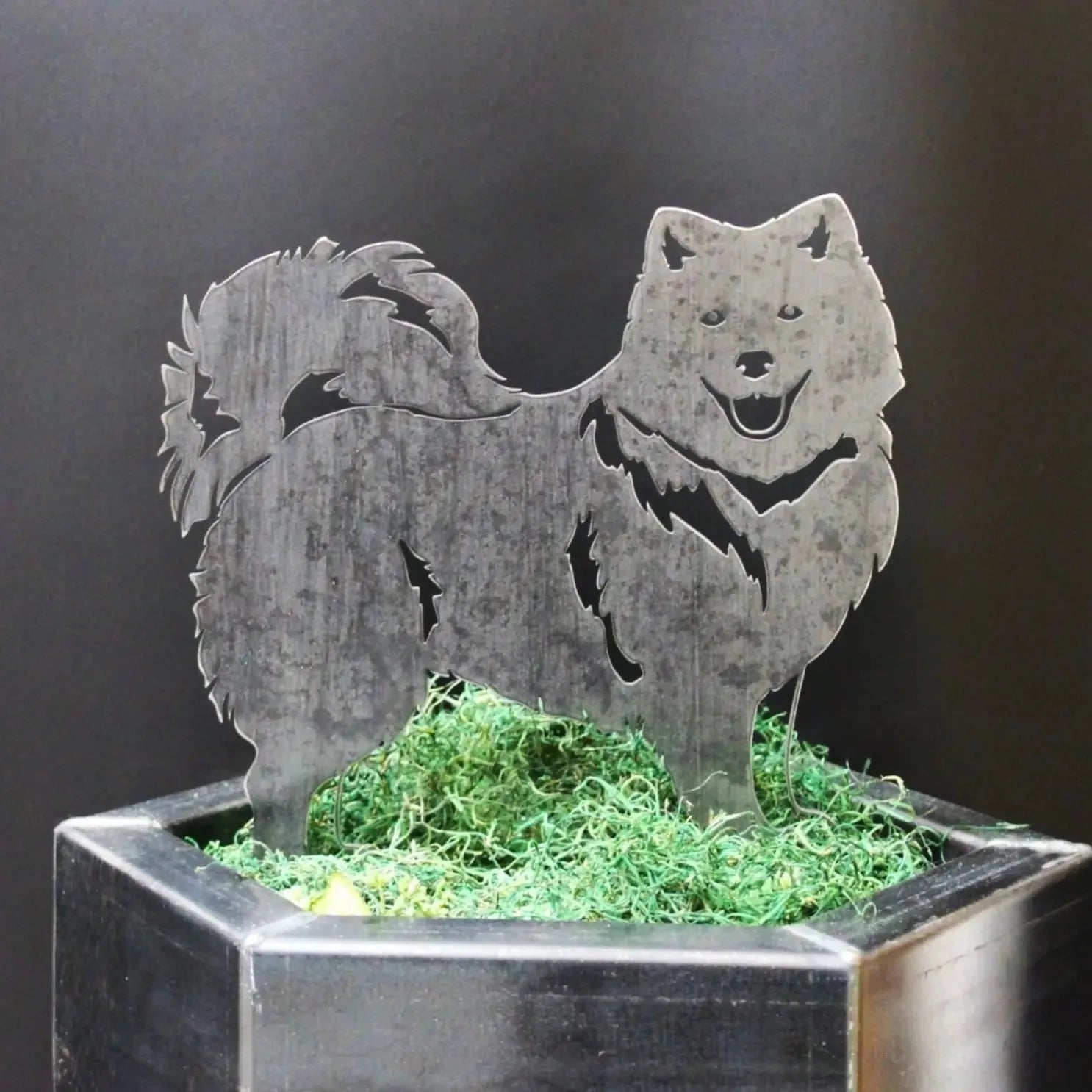 Japanese Spitz metal silhouette in Corten steel, showcasing intricate detailing and a rustic finish, placed atop green moss.