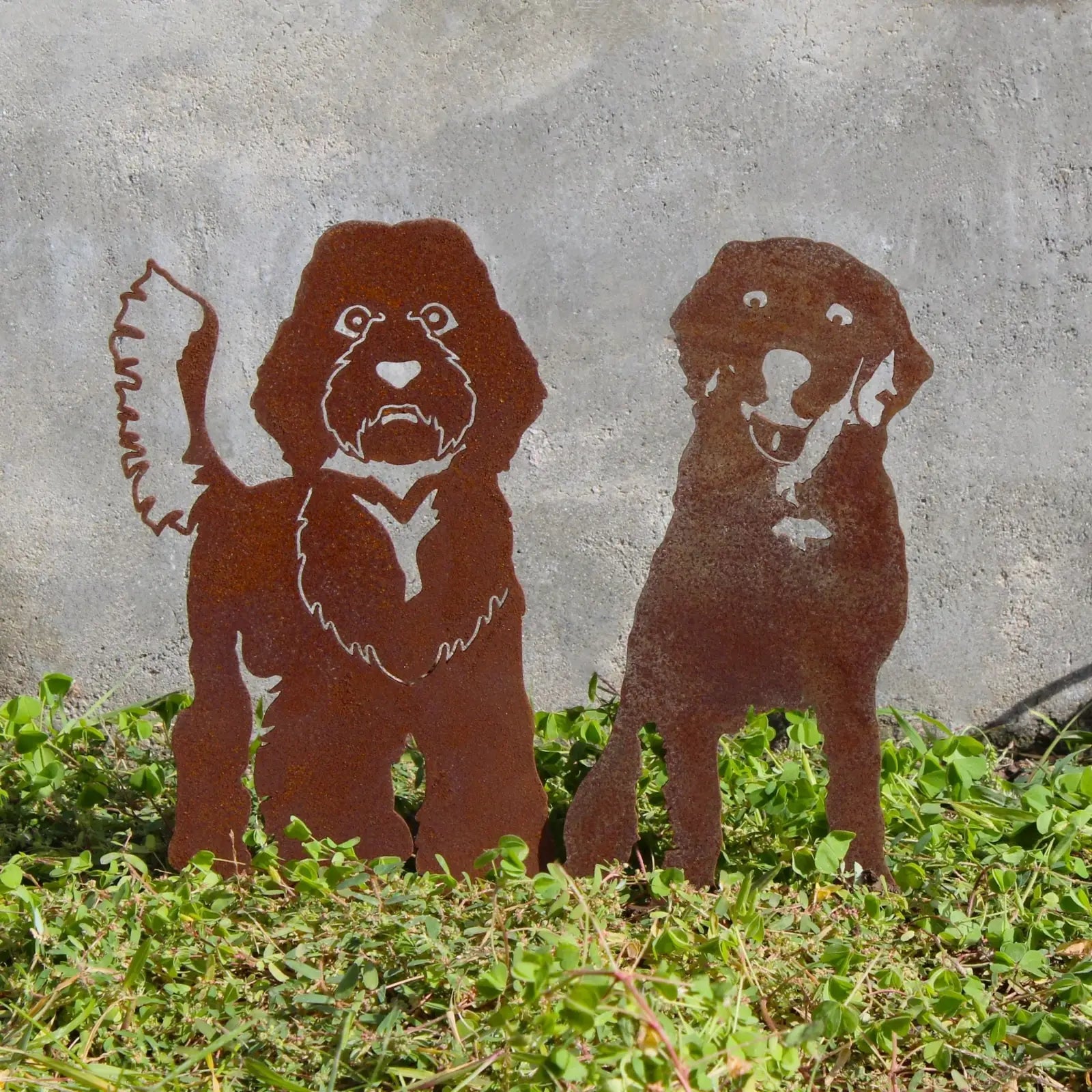 Rusty metal silhouette of a Labradoodle and a retriever, showcasing artistic design, set against green grass.