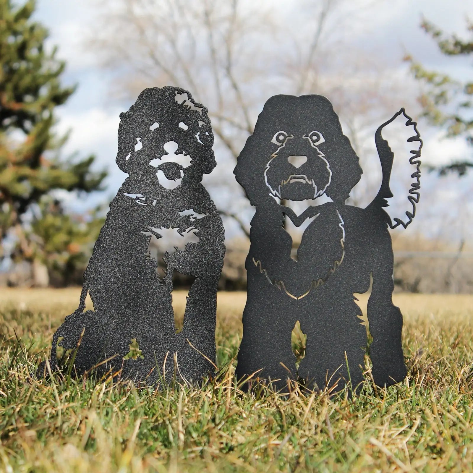 Labradoodle metal silhouettes in black, handcrafted from sturdy steel, displayed in grass against a blue sky.