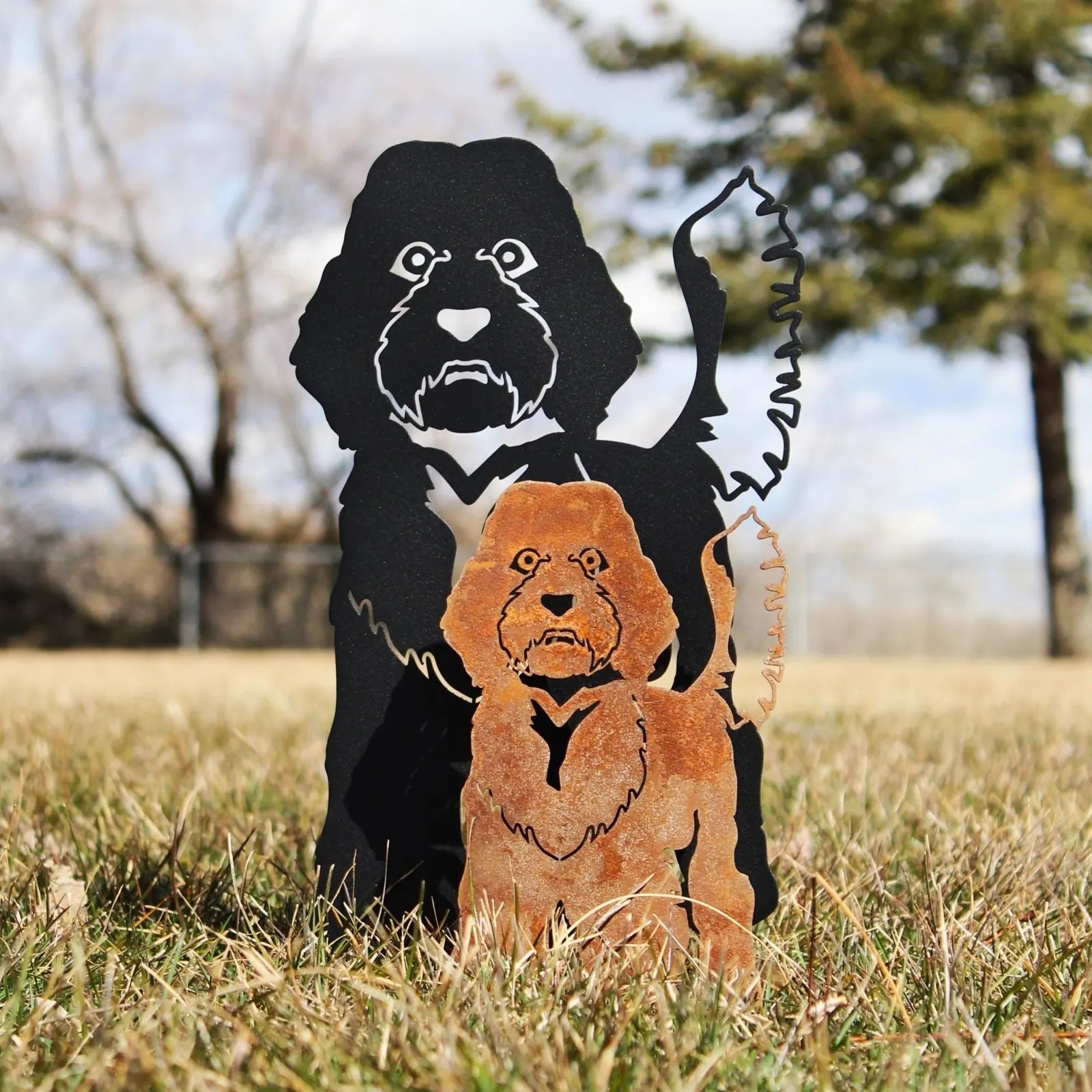 Labradoodle metal silhouettes in black and rust patina, showcasing detailed artistic design in a grassy outdoor setting.