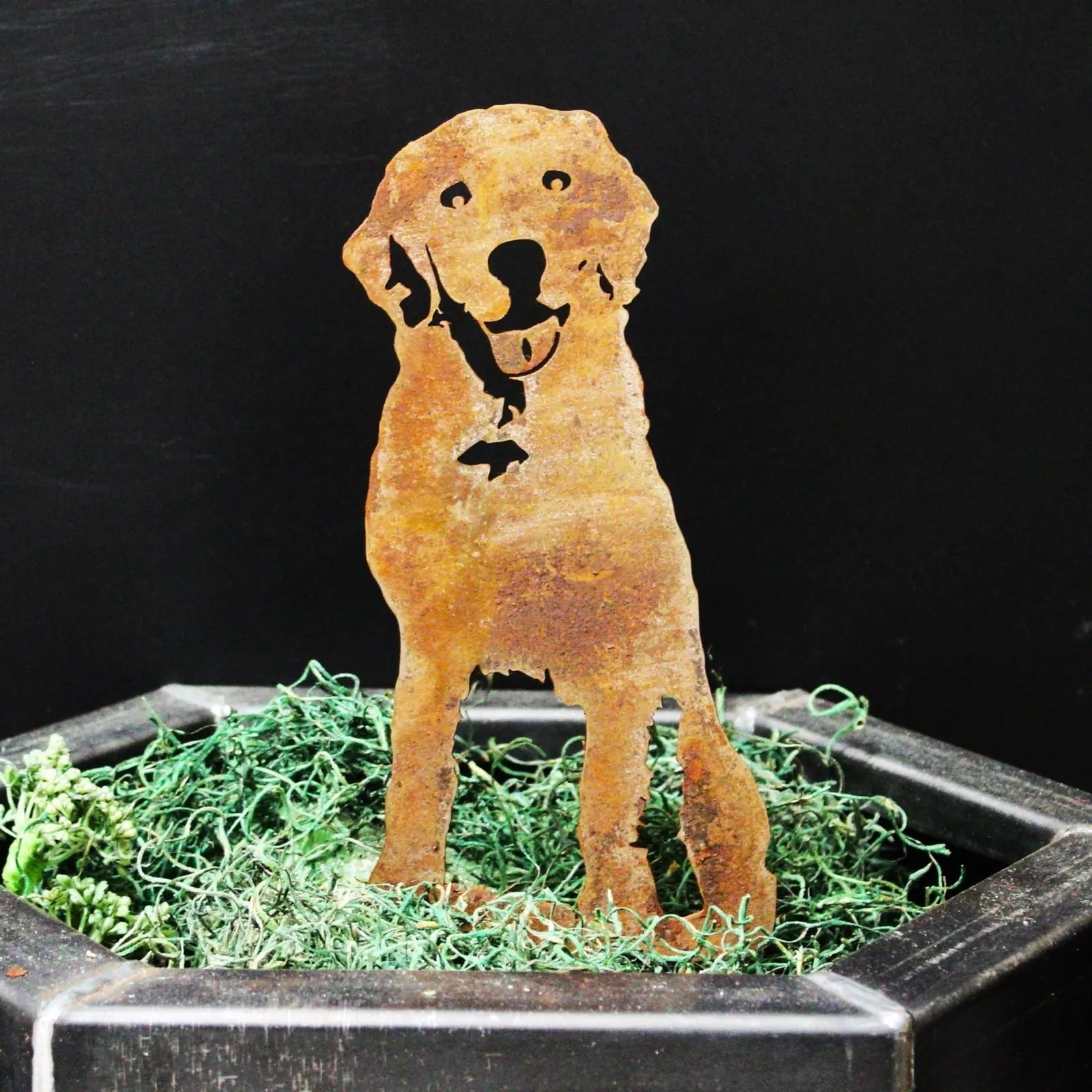 Handcrafted rusted metal Labrador Retriever sculpture, featuring a joyful expression, placed in green decor.
