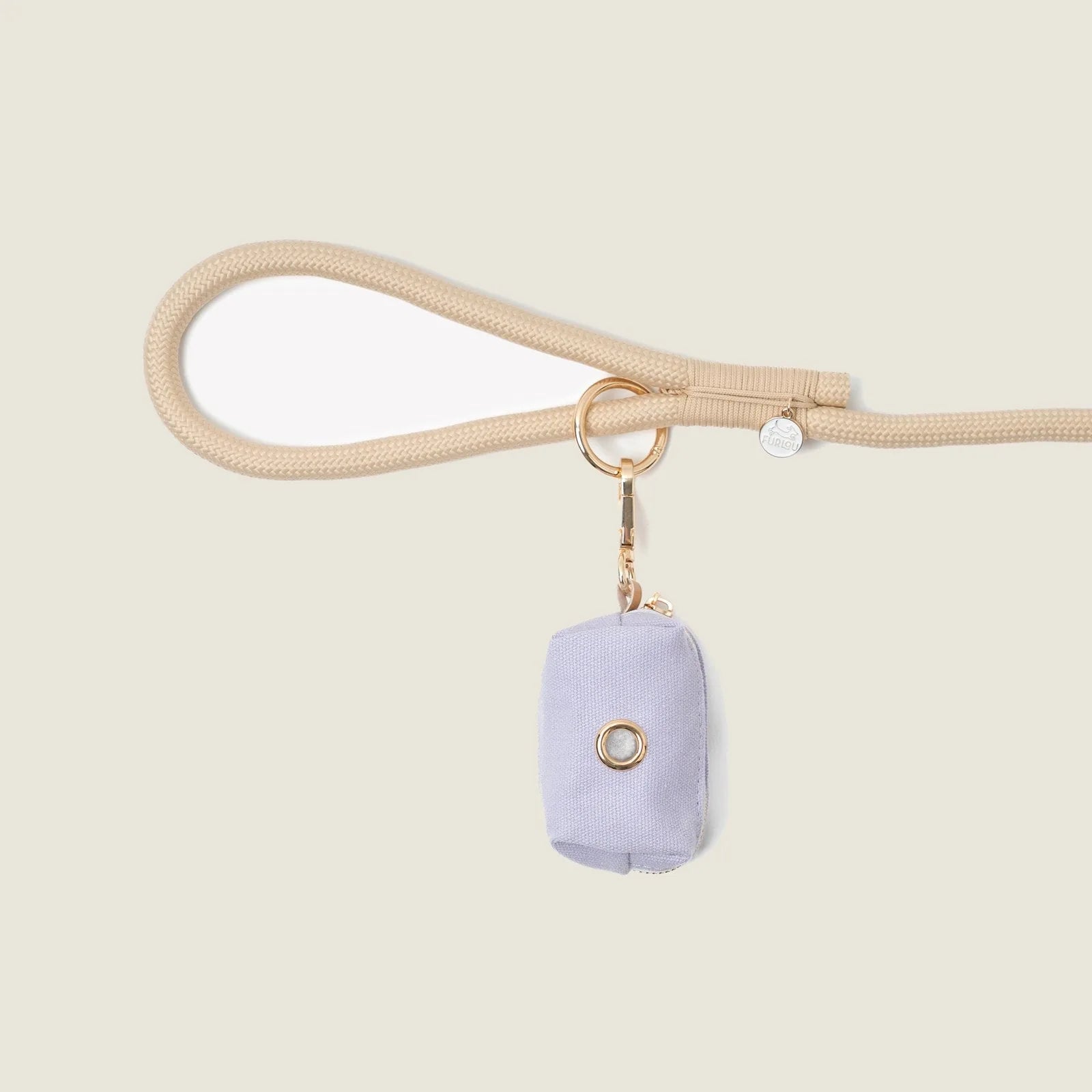 Lavender poop bag holder by FURLOU attached to a beige leash, featuring a gold clip for easy access.