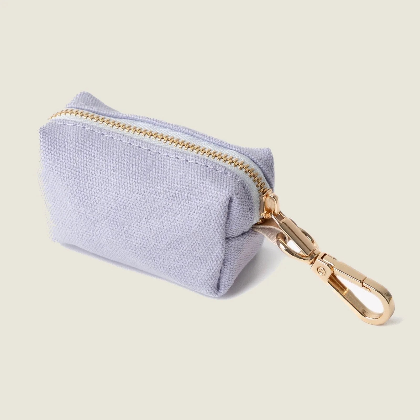 Lavender poop bag holder with gold zipper and clip, compact design for convenient dog walking.