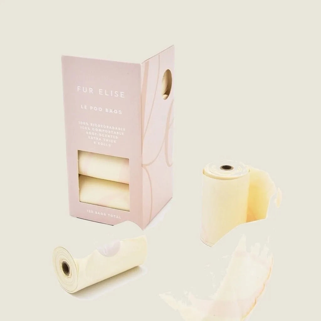 Biodegradable rose-scented Le Poo Bags in a pink box, with rolls displayed for easy access during dog walks.