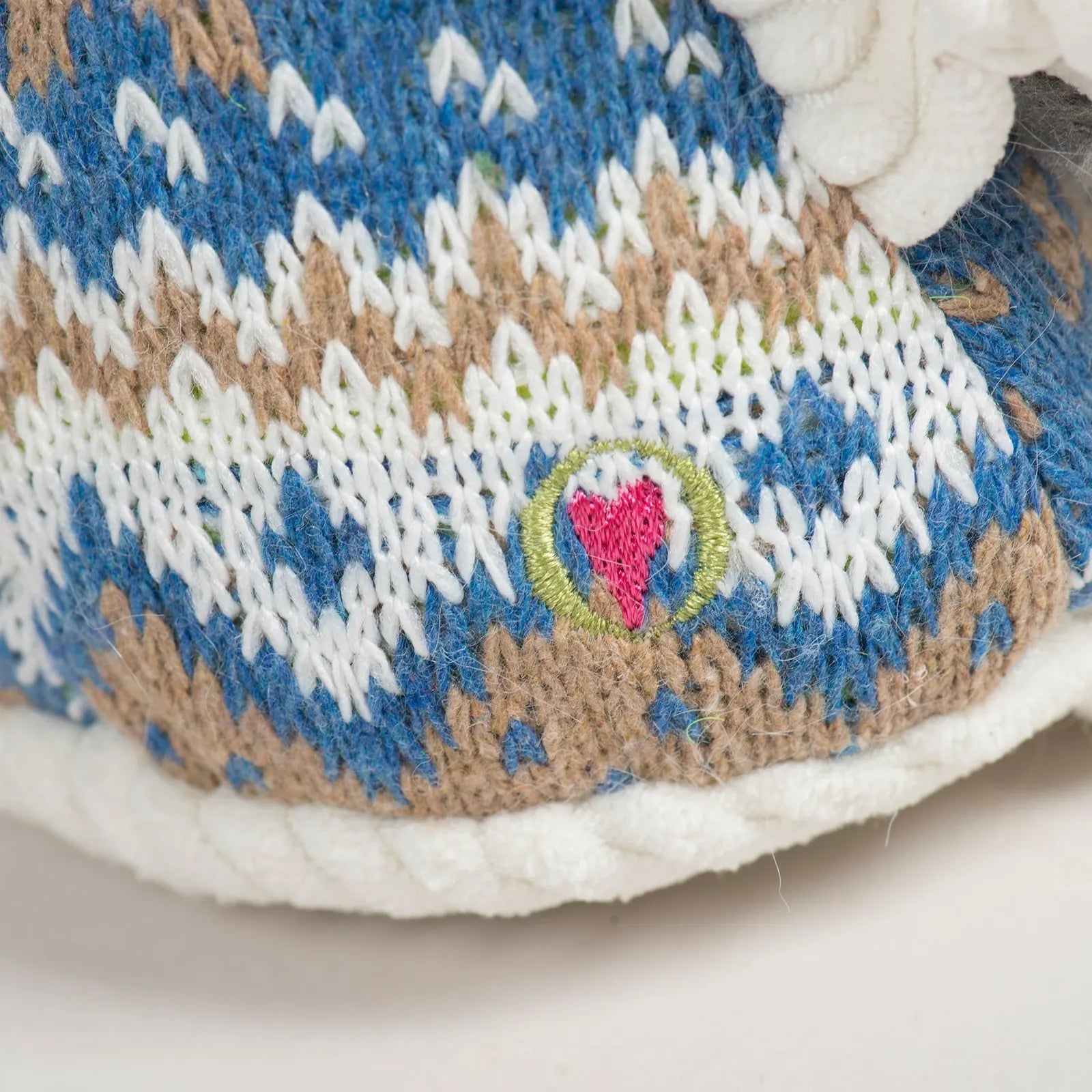 Close-up of Leo Lamb's Nordic blue knit sweater featuring white and brown patterns and an embroidered heart logo.