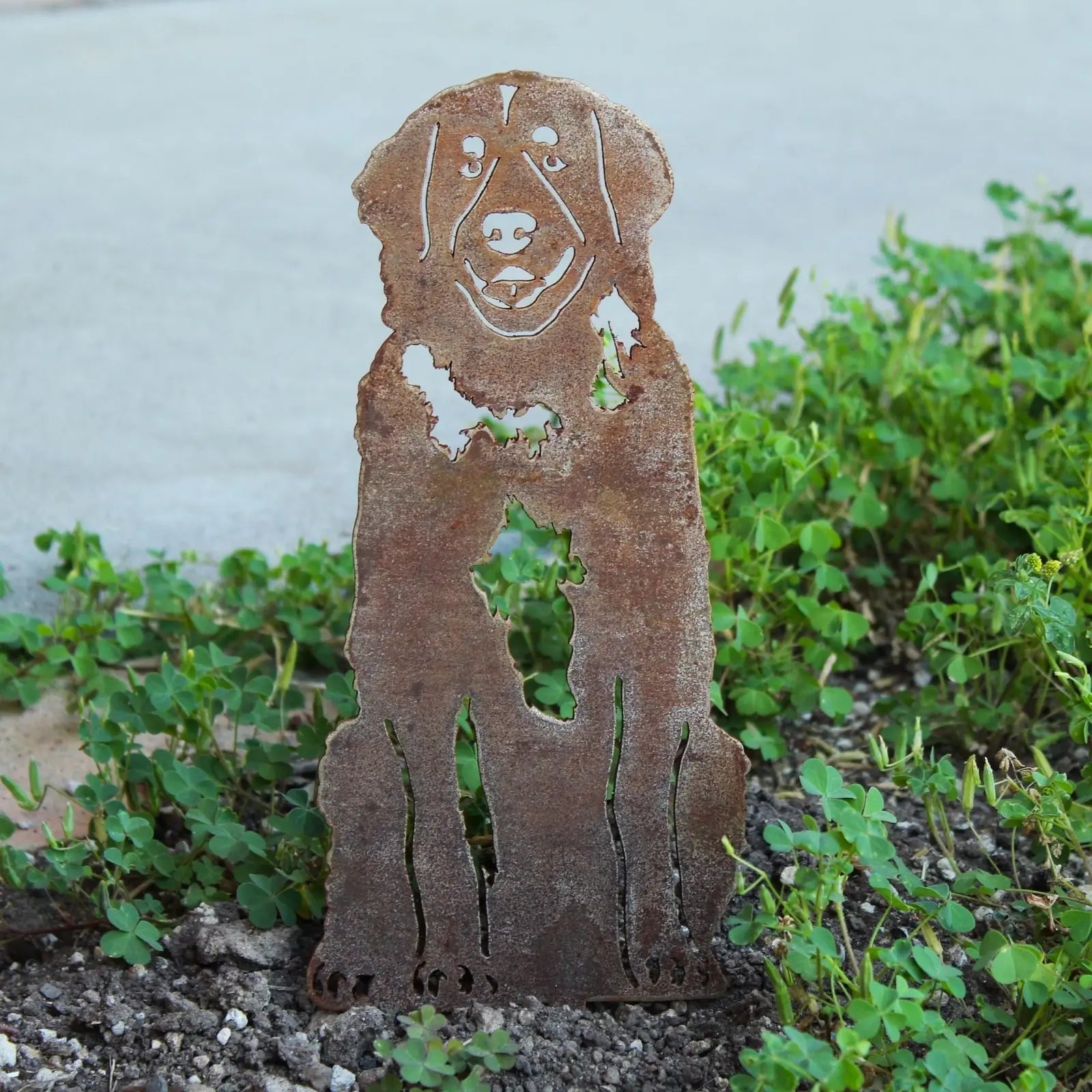 Leonberger metal silhouette in weathered rust finish, set among greenery, perfect for outdoor dog decor.