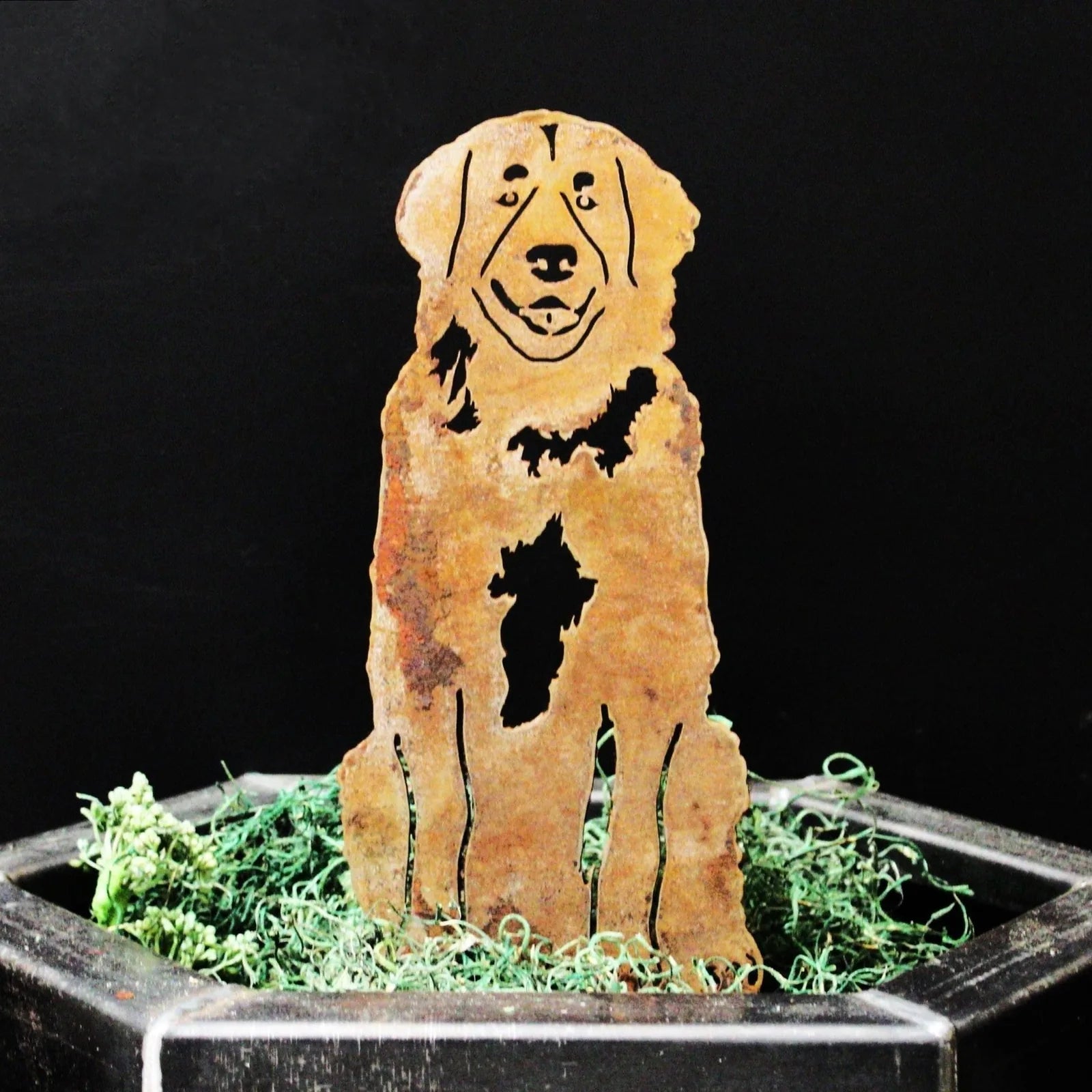 Corten steel Leonberger silhouette with rust patina, displaying intricate cutouts, set in green moss decor.