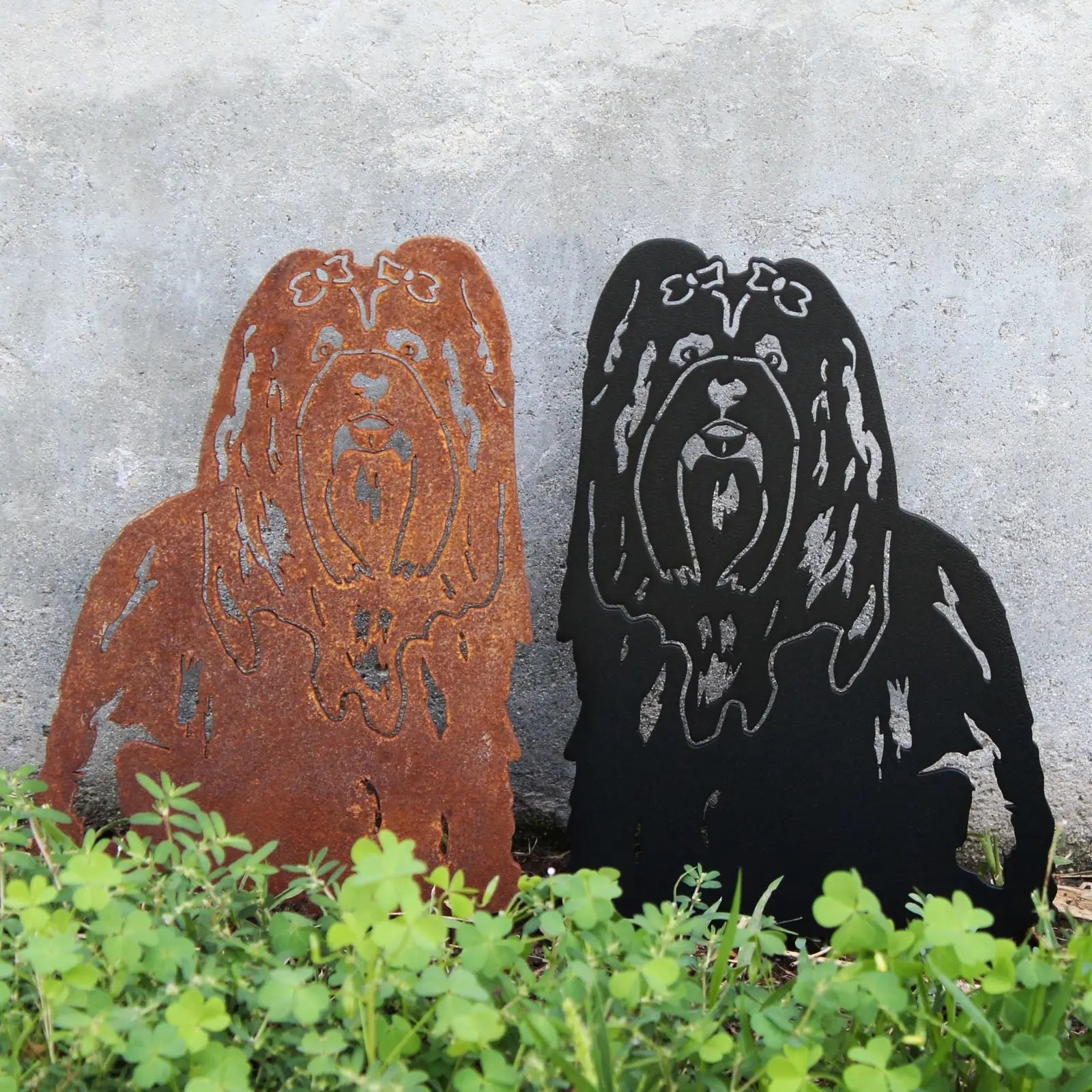 Lhasa Apso metal silhouette wall art in Corten steel and matte black, perfect for outdoor decor, resting on green grass.