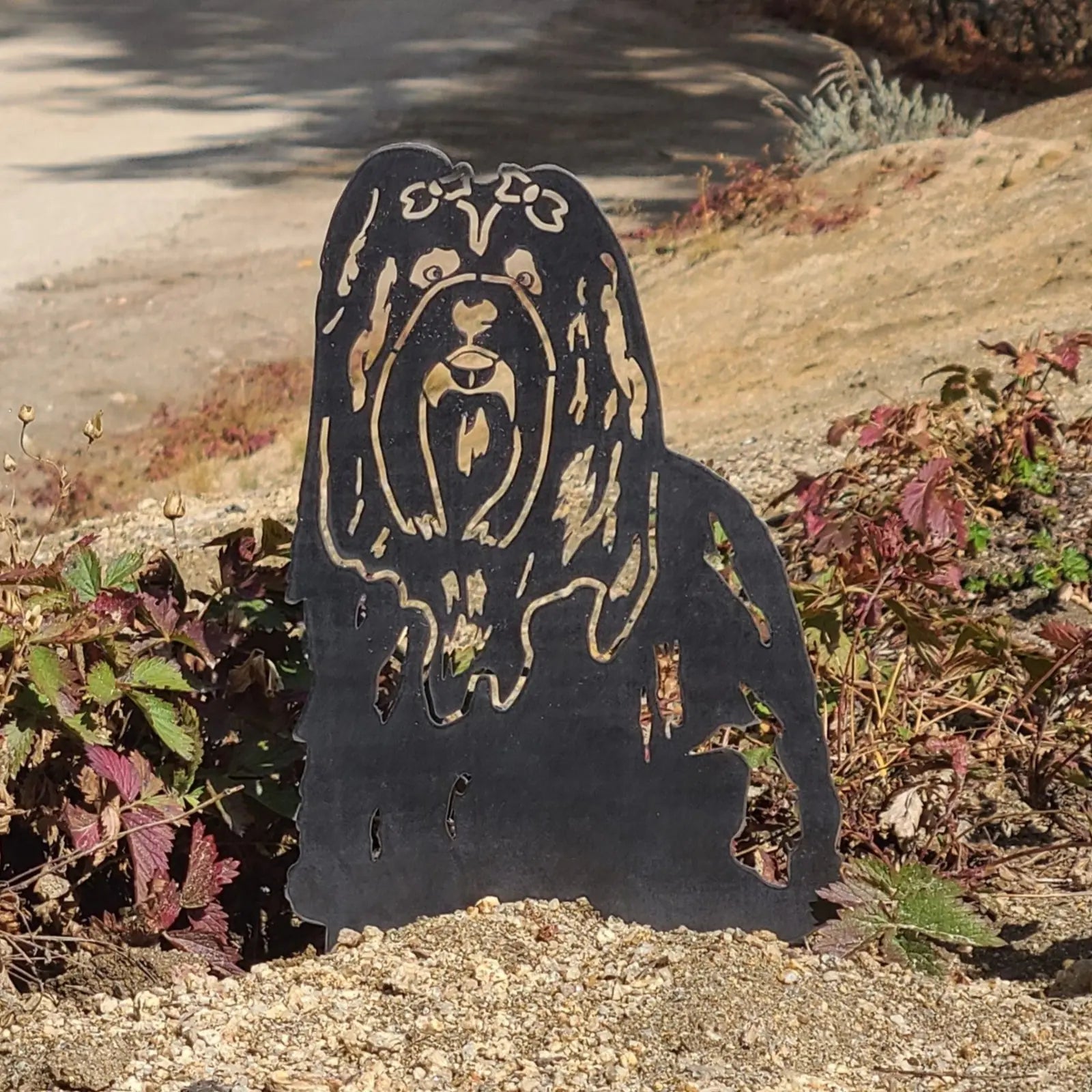 Lhasa Apso metal silhouette in matte black against greenery, showcasing intricate cut-out details and durable design.