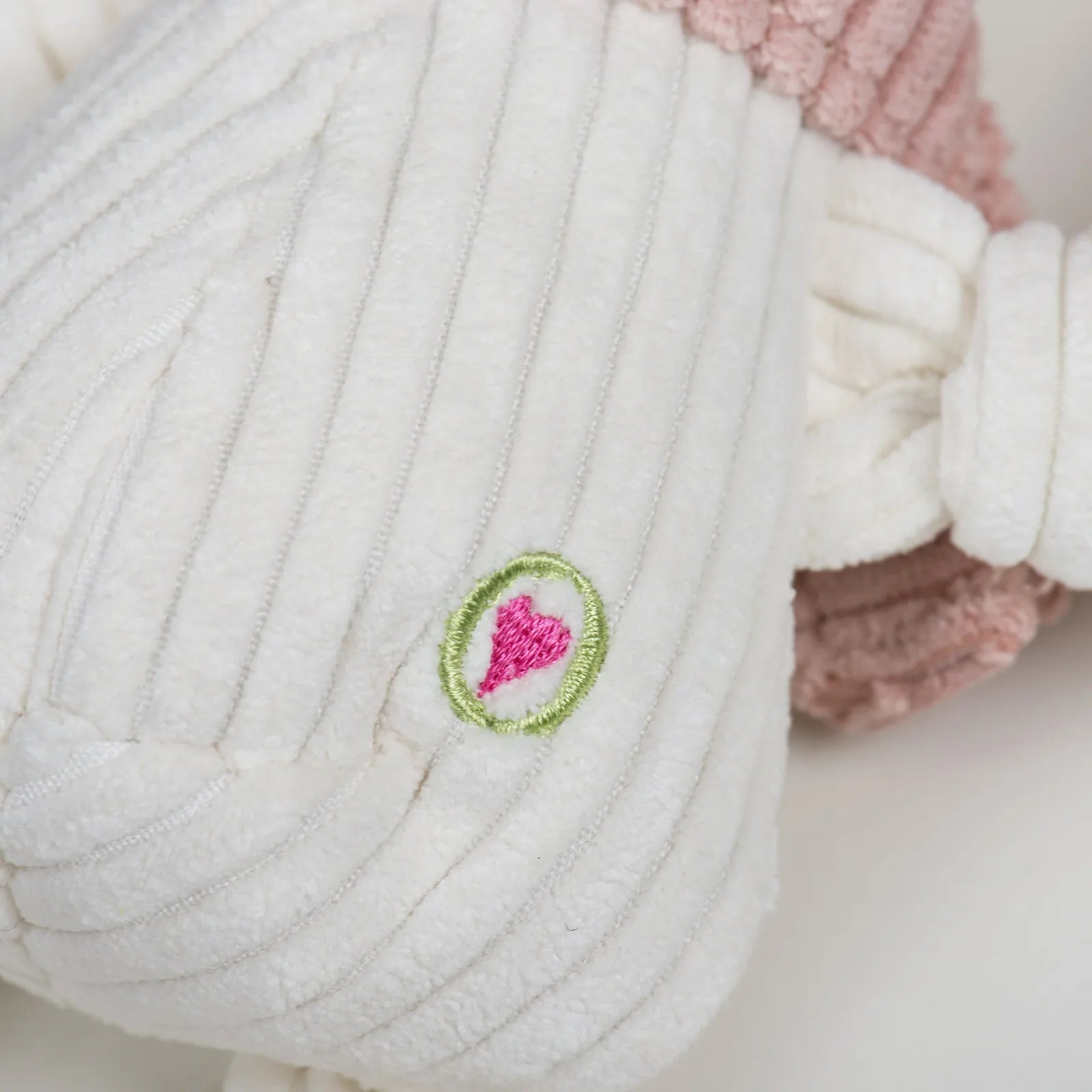 Close-up of Lillie Llama Knottie® plush dog toy, featuring soft cream fabric with a pink scarf and heart embroidery.