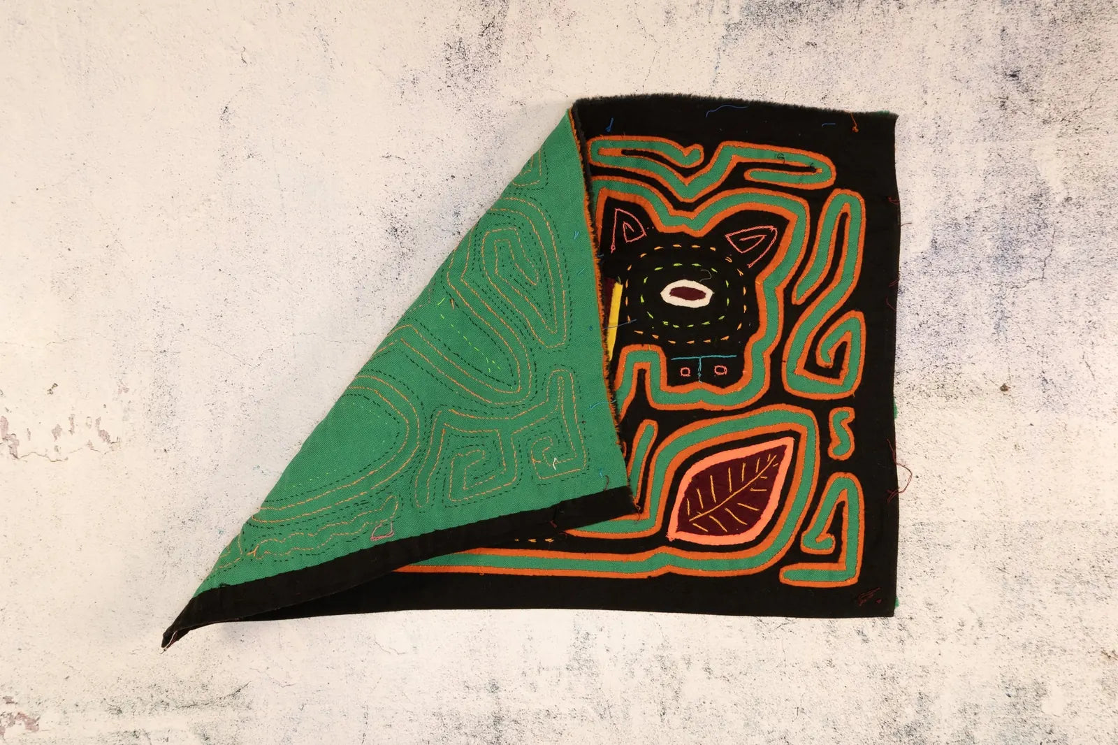 Hand-stitched black Mola featuring a geometric dog design in orange and green, crafted by Guna artisans from Panama.