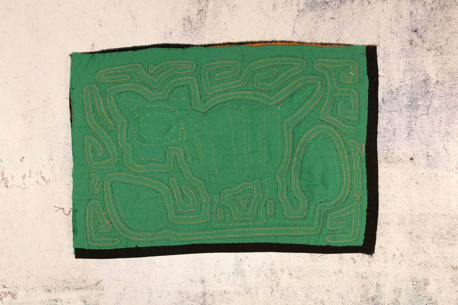 Bright green Mola featuring a dog design with intricate yellow and orange stitching; handmade from fair trade textiles.