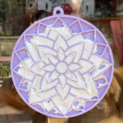 Pastel purple lotus lick mat with varied textures and suction cups, holding a soft treat for mental stimulation.