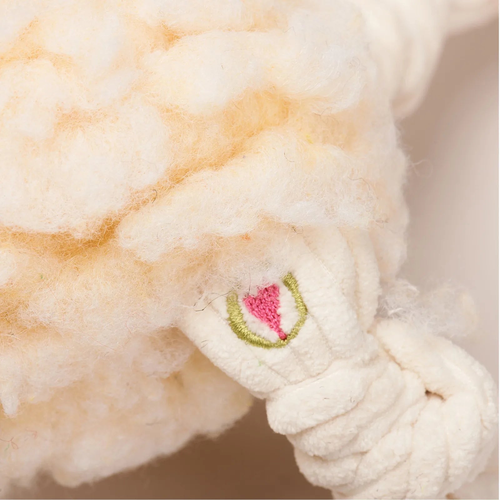 Soft cream-colored plush dog toy with knotted limbs and an embroidered flower design, perfect for cuddling and play.
