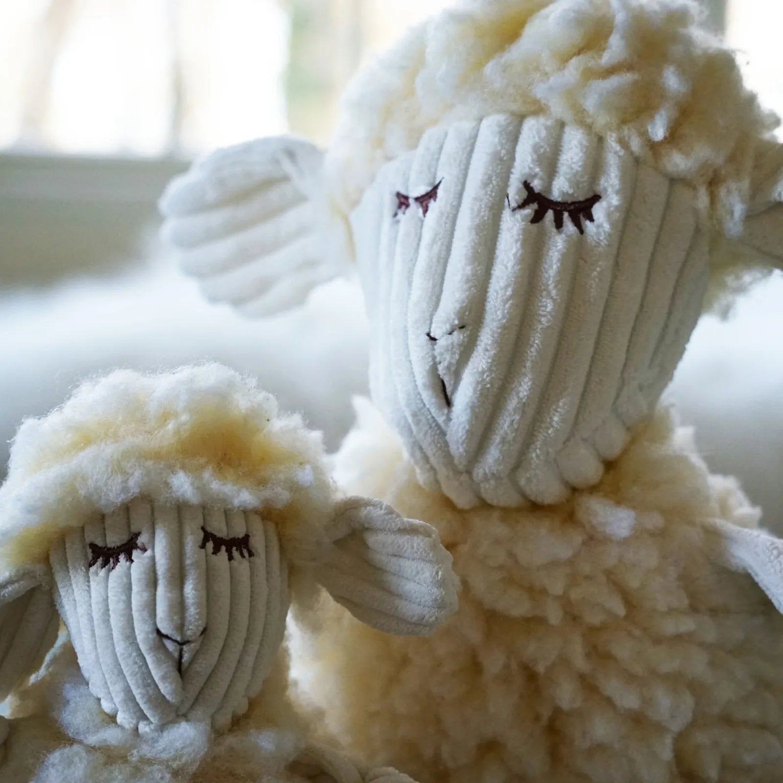 Soft, plush, cream-colored Louise Lamb dog toys with knotted limbs and sweet facial features, in small and large sizes.