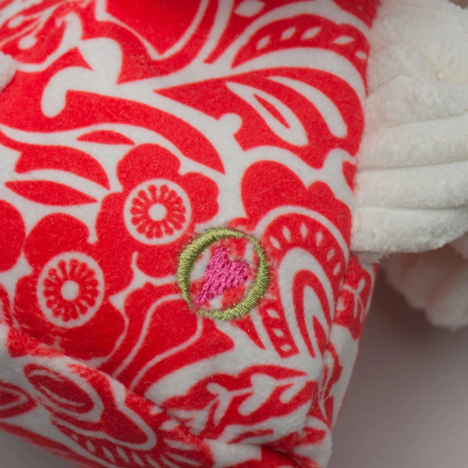 Red and white plush dog toy featuring a floral pattern and a green embroidered detail, part of the Lucky Dragon Knottie® c...