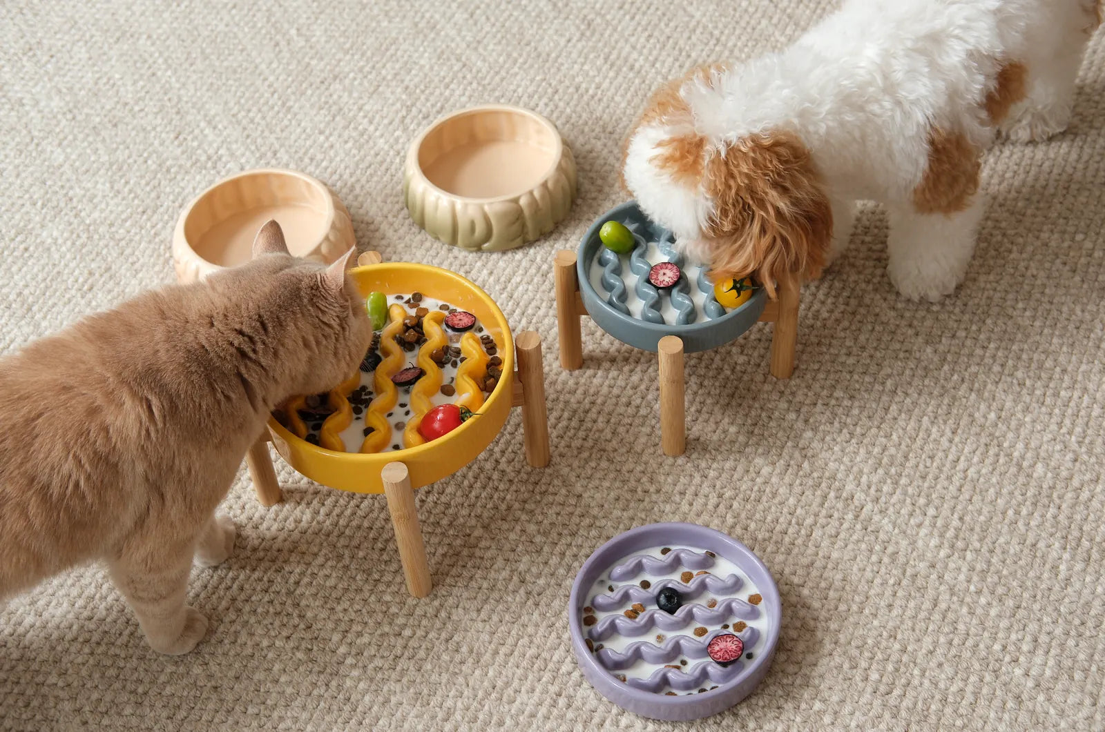 Yellow slow feeder dog bowl with wavy pattern, paired with a pet dog and cat enjoying food, includes a blue bowl nearby.