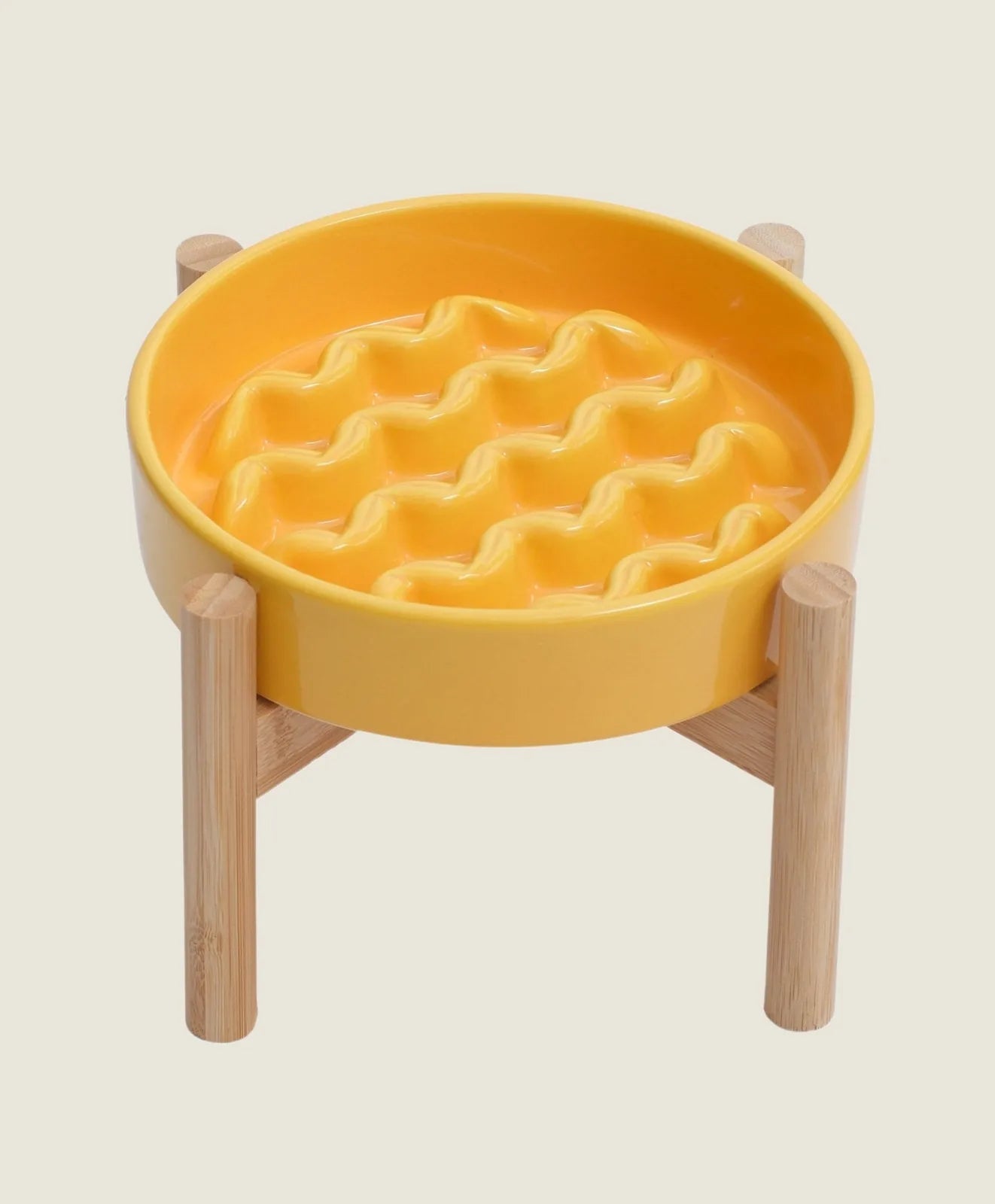 Yellow ceramic slow feeder dog bowl with wavy pattern and wooden stand, promoting slow eating for better digestion.