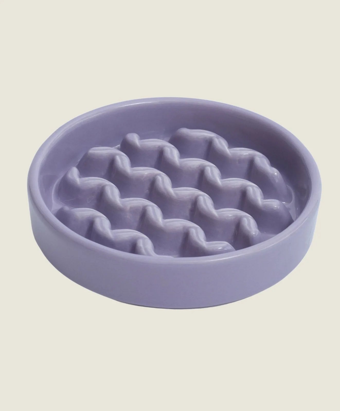 Round purple ceramic slow feeder dog bowl with wave-patterned design to encourage slower eating.