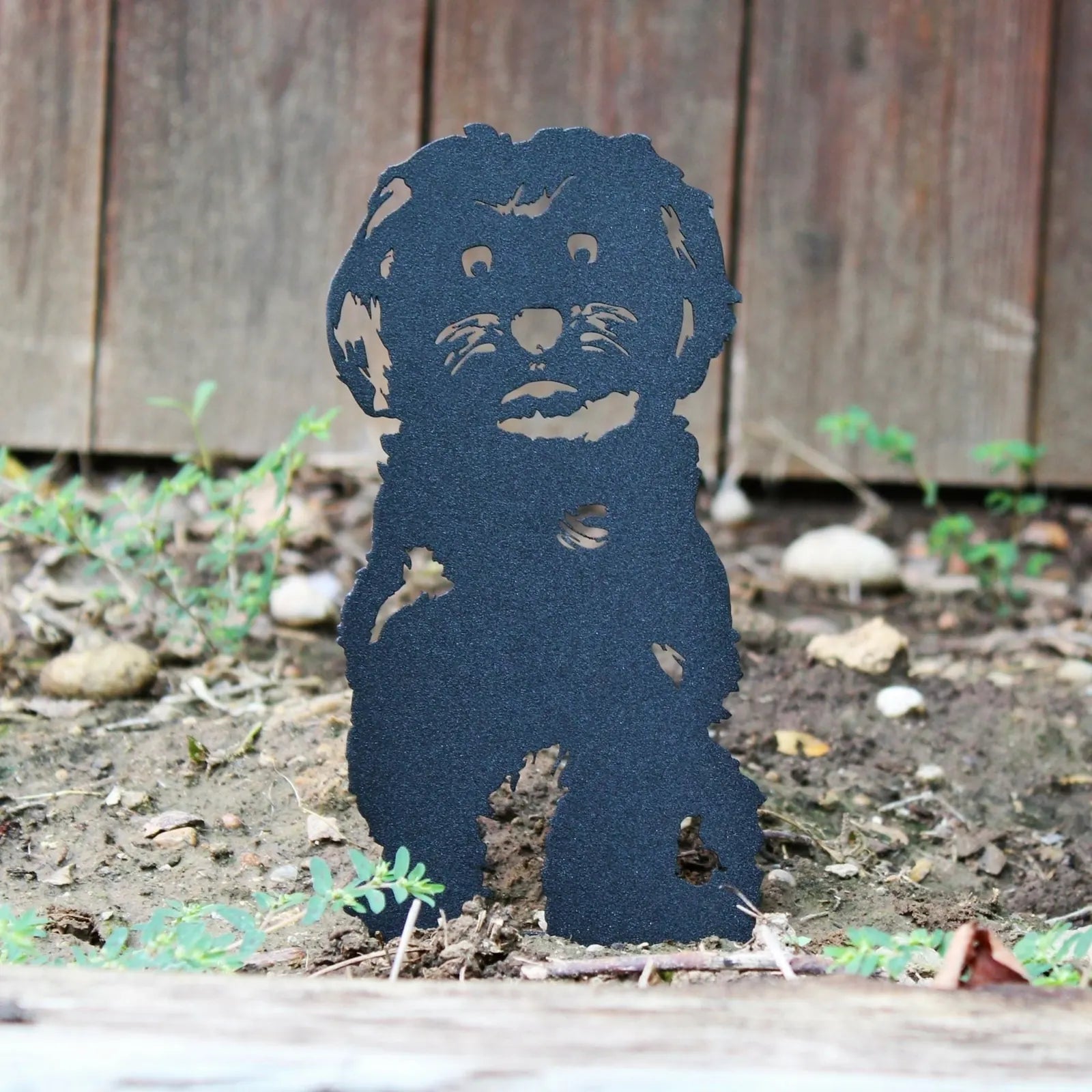 Black metal Maltese silhouette standing in soil, designed for outdoor dog decor, showcasing intricate cut-out details.