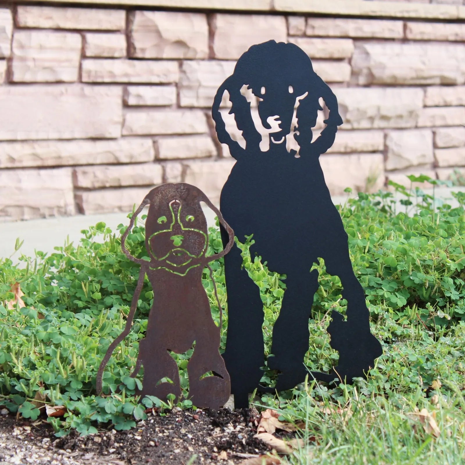 Maltipoo metal silhouette art in rust and black, displayed outdoors among green foliage and stone background.