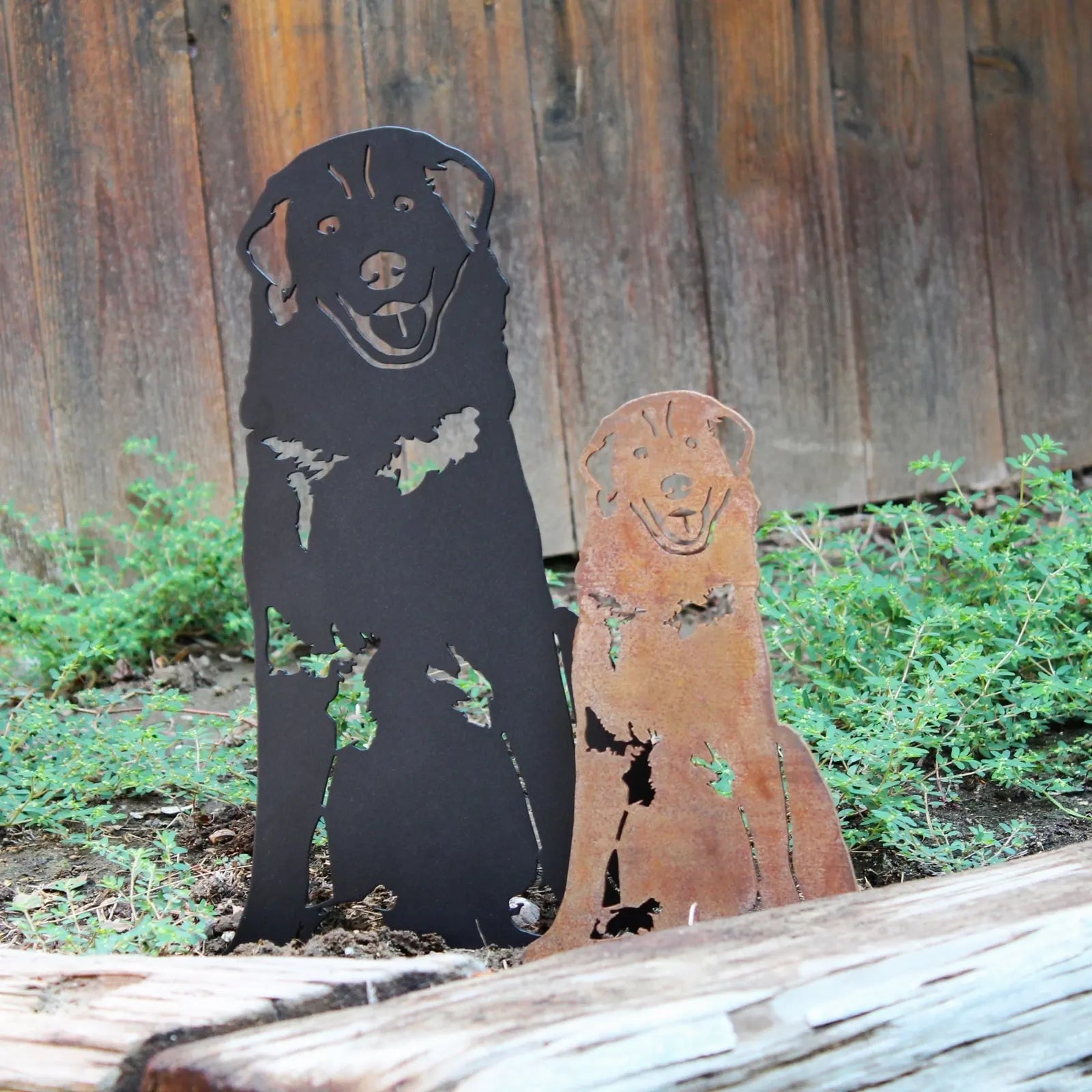 Black and rust-colored Maremma Sheepdog metal silhouettes set in garden greenery, showcasing unique finishes and designs.