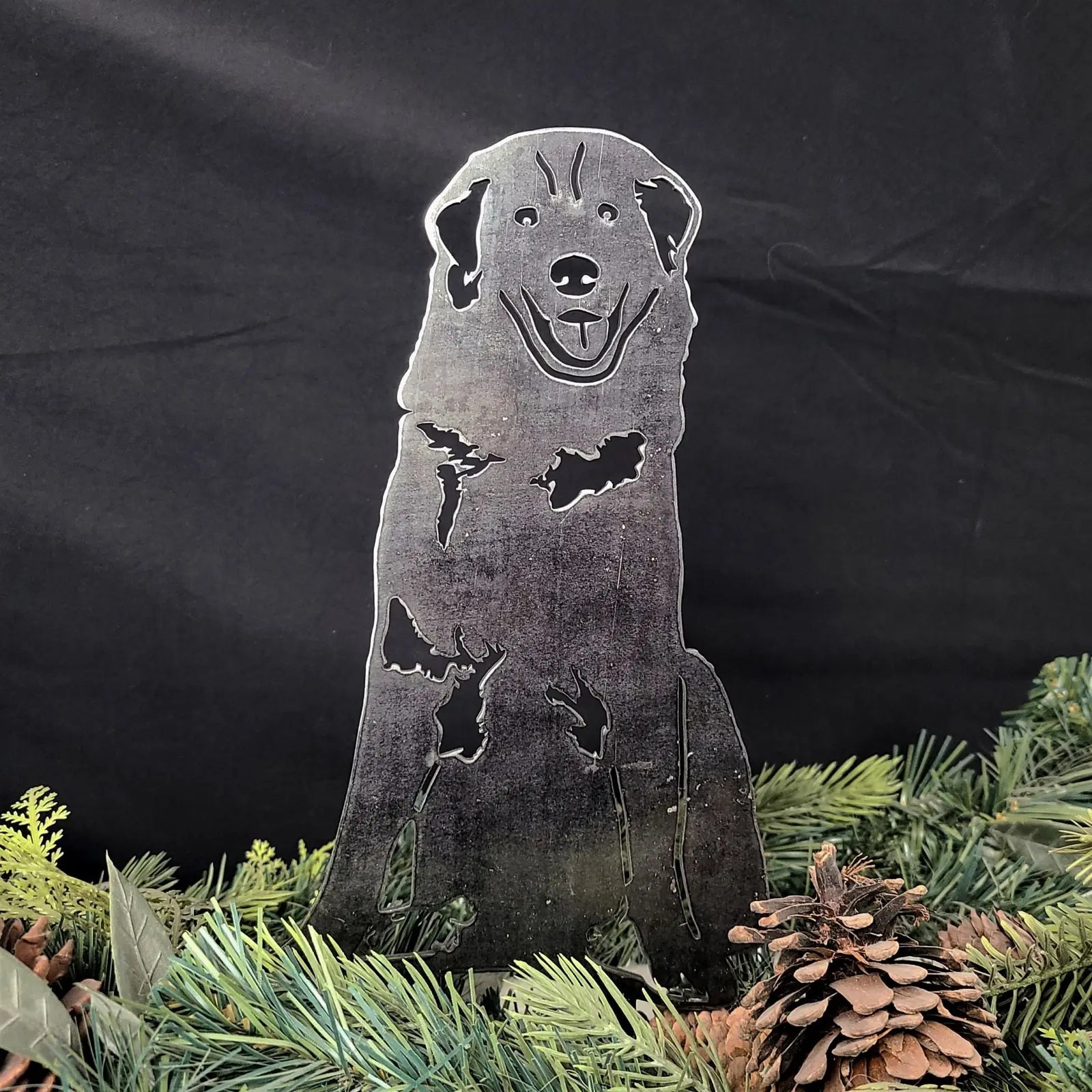Handmade Maremma Sheepdog metal silhouette in a rustic finish, surrounded by greenery and pinecones.