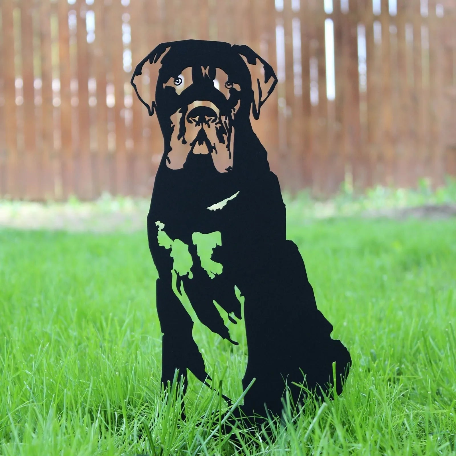 Mastiff silhouette in matte black metal sits in green grass, ideal for outdoor dog decor.