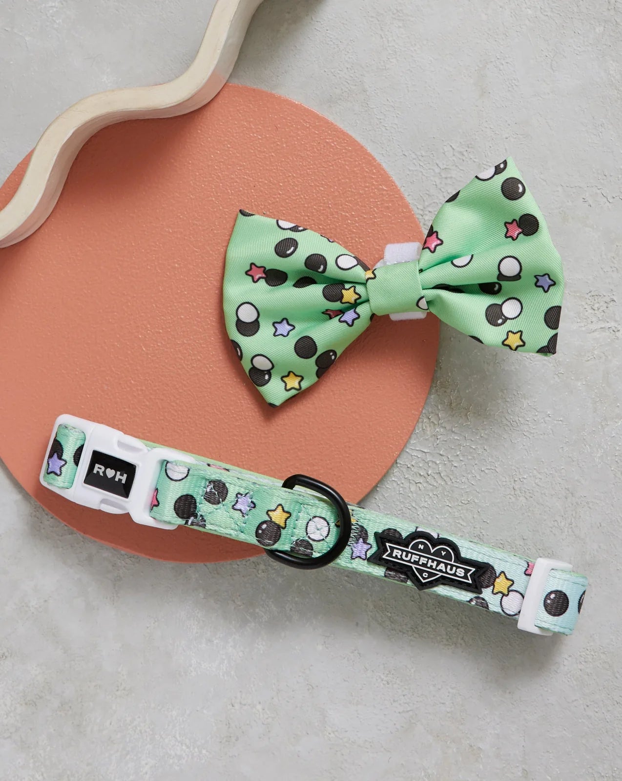 Matcha boba dog collar in mint green with colorful dots and stars, paired with a matching bowtie on a round background.