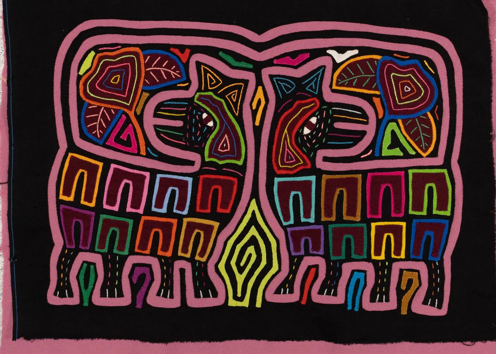 Vibrant hand-stitched Mola tapestry featuring geometric animal designs in multicolored threads on a black background.