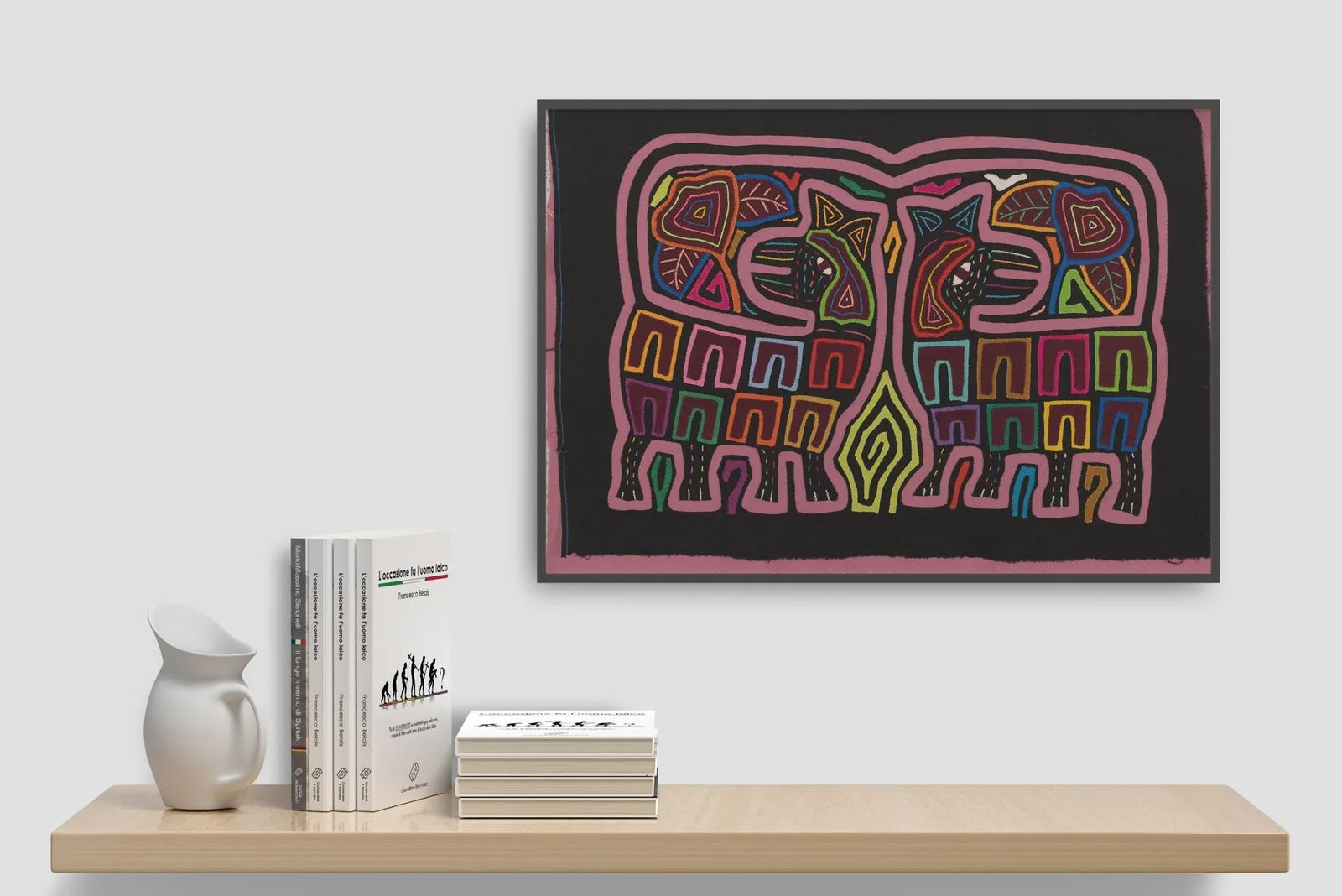 Colorful hand-stitched Mola art featuring two elephants in geometric designs, displayed on a minimalist shelf.