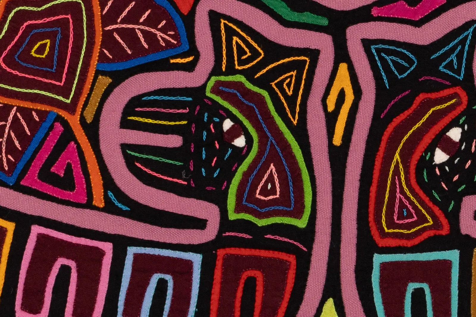Colorful geometric patterns in stitched fabric showcasing vibrant hues of pink, green, and red in a Mola design.