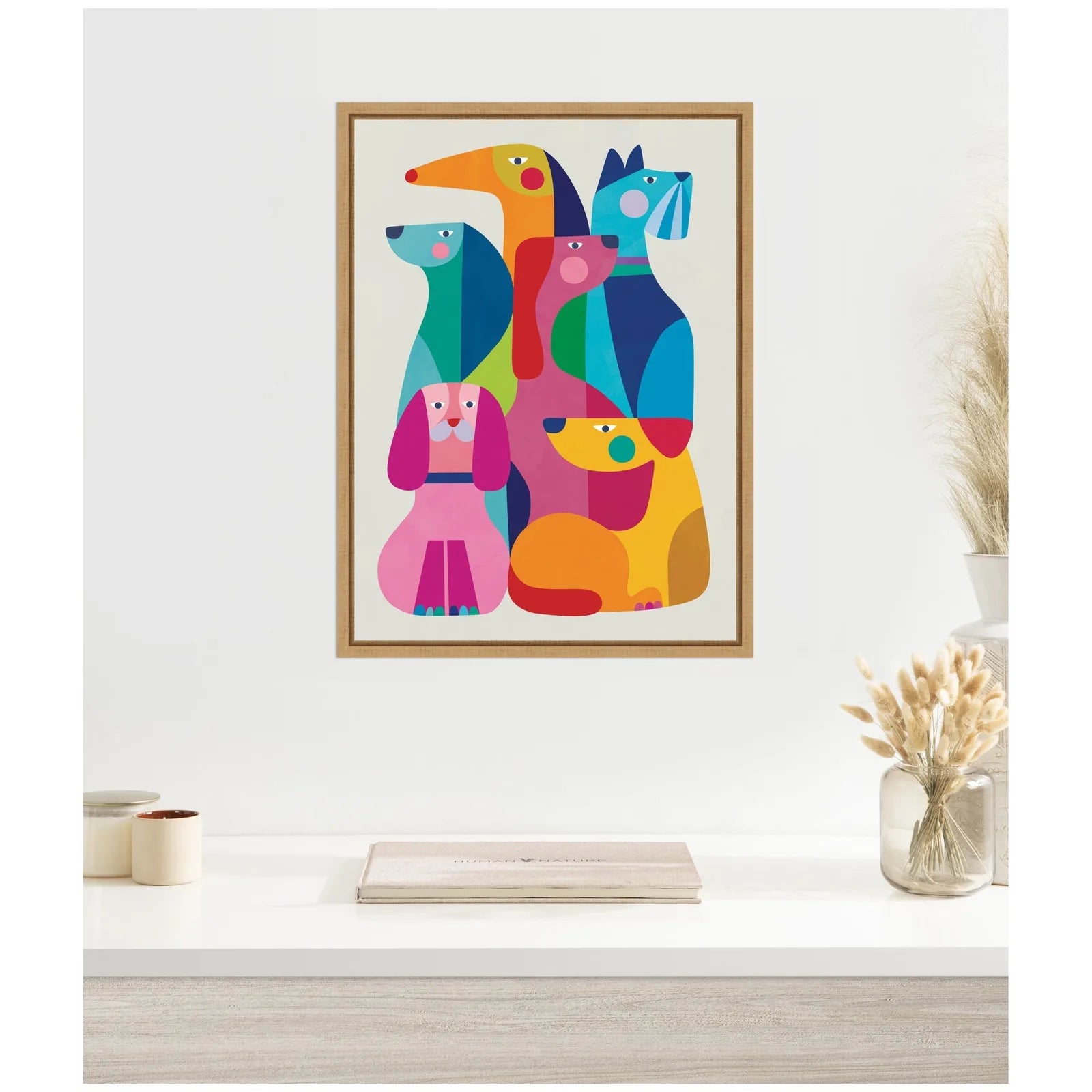 Framed abstract canvas art featuring colorful dogs in various shapes by Rachel Lee, set in a light wooden frame.