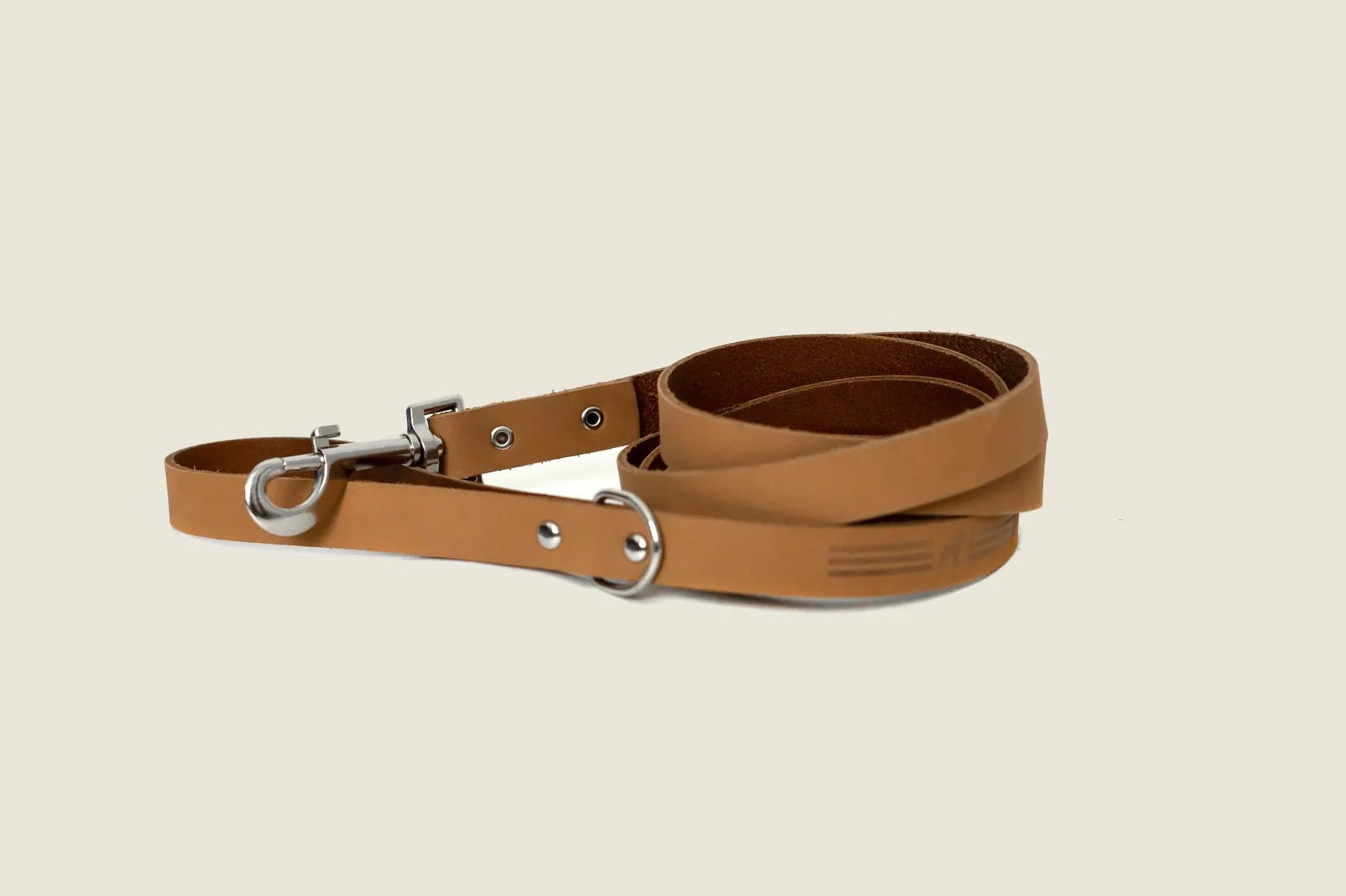 Khaki leather dog leash with a sleek design, featuring a metal clip and additional d-ring for convenience.