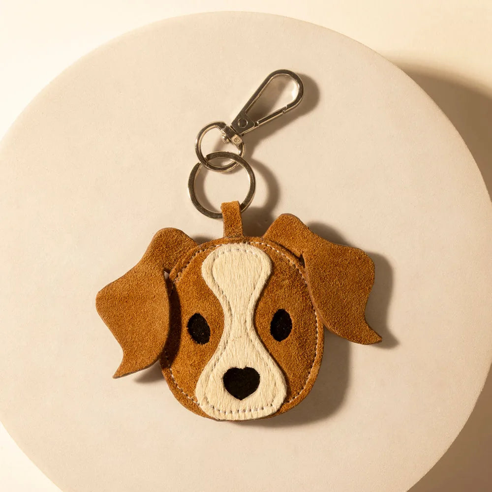 Rawhide tan leather dog charm keychain featuring stitched details and a clip for easy attachment to bags or keys.