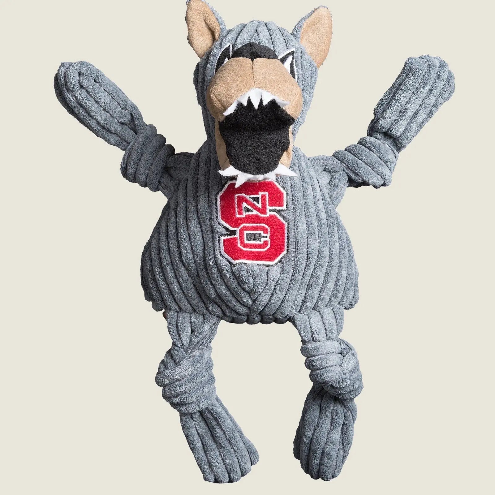 Gray plush dog toy shaped like Mr. Wuf, featuring knotted limbs and an NC State logo on its chest.