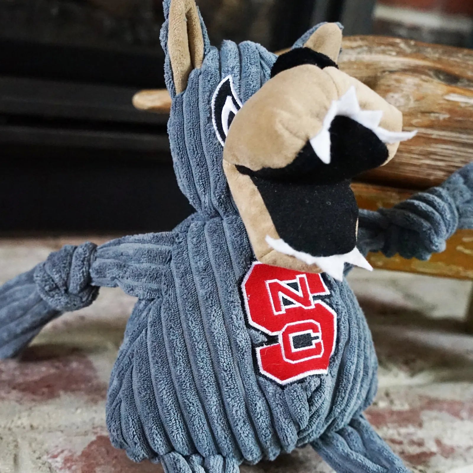Plush Mr. Wuf dog toy in gray corduroy with knotted limbs, featuring an embroidered NC State logo.