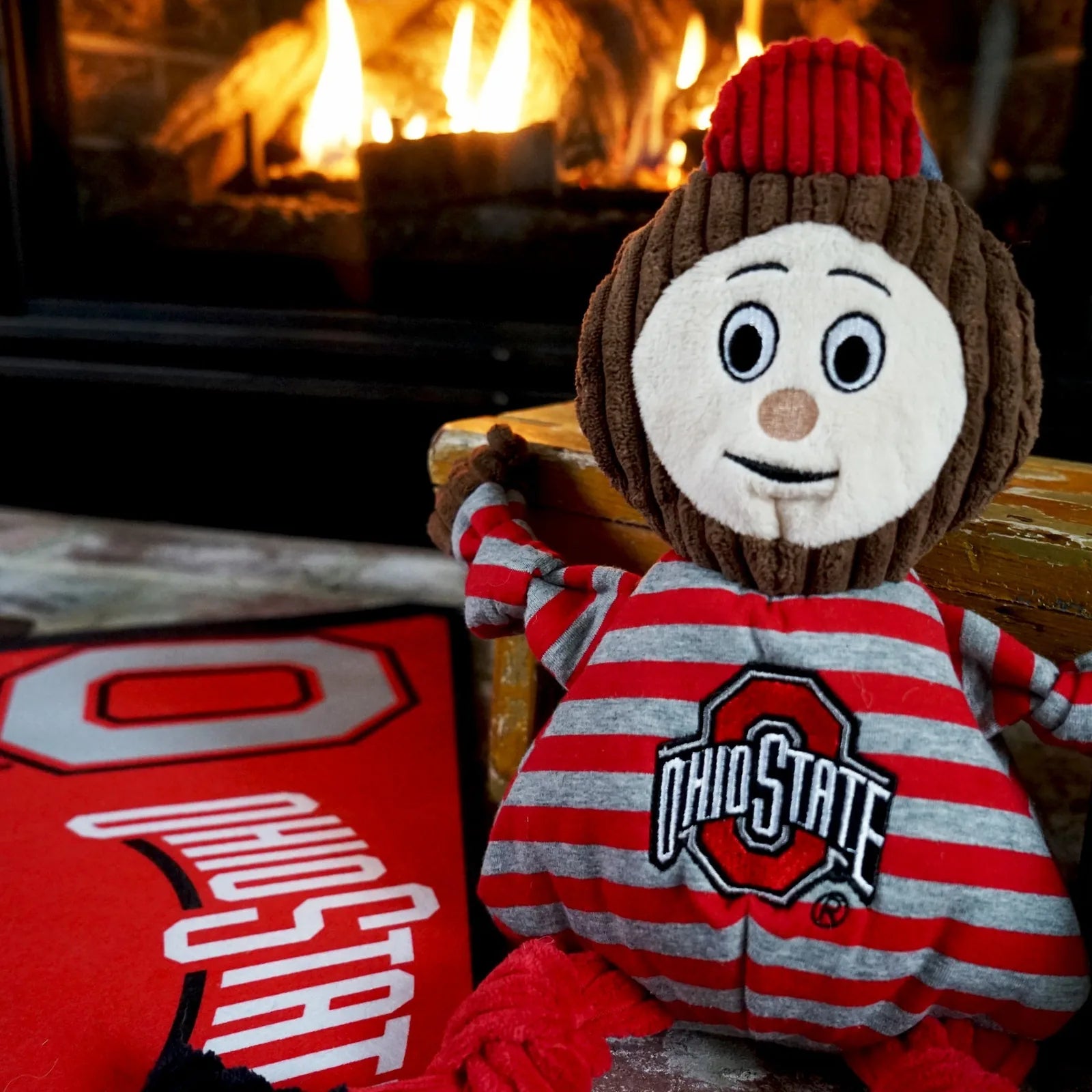 Plush Brutus the Buckeye toy in gray and red stripes with knotted limbs, featuring an Ohio State logo and smiling face.