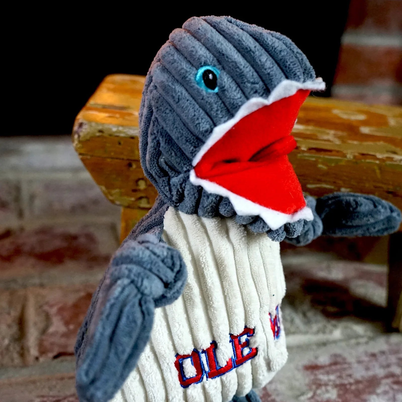 Gray and cream plush dog toy shaped like a shark, featuring a red mouth and "OLE MISS" embroidered on the body.
