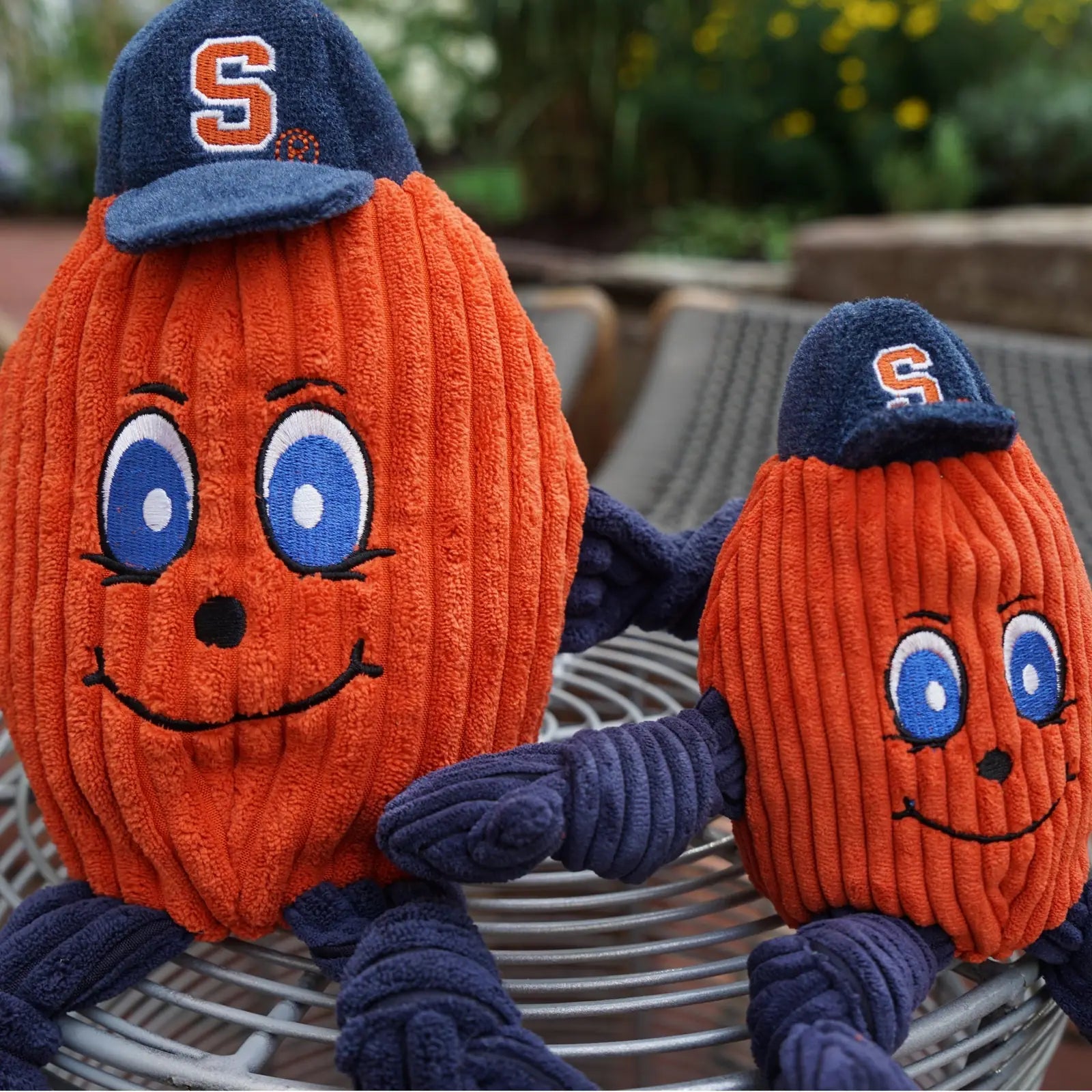 Plush orange dog toys resembling Otto the Orange, featuring blue eyes, smiles, and navy hats, perfect for playtime.