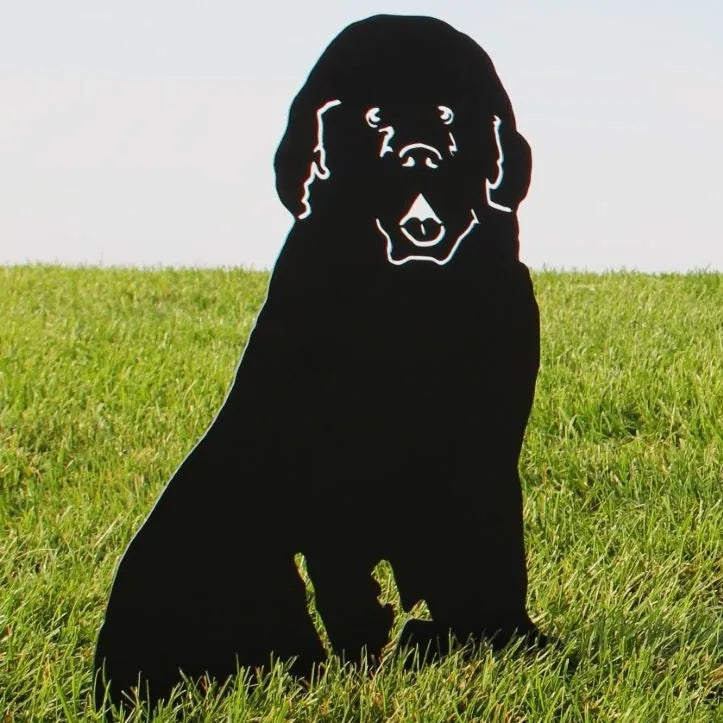 Black metal silhouette of a Newfoundland dog sitting on green grass, designed for outdoor garden decor.