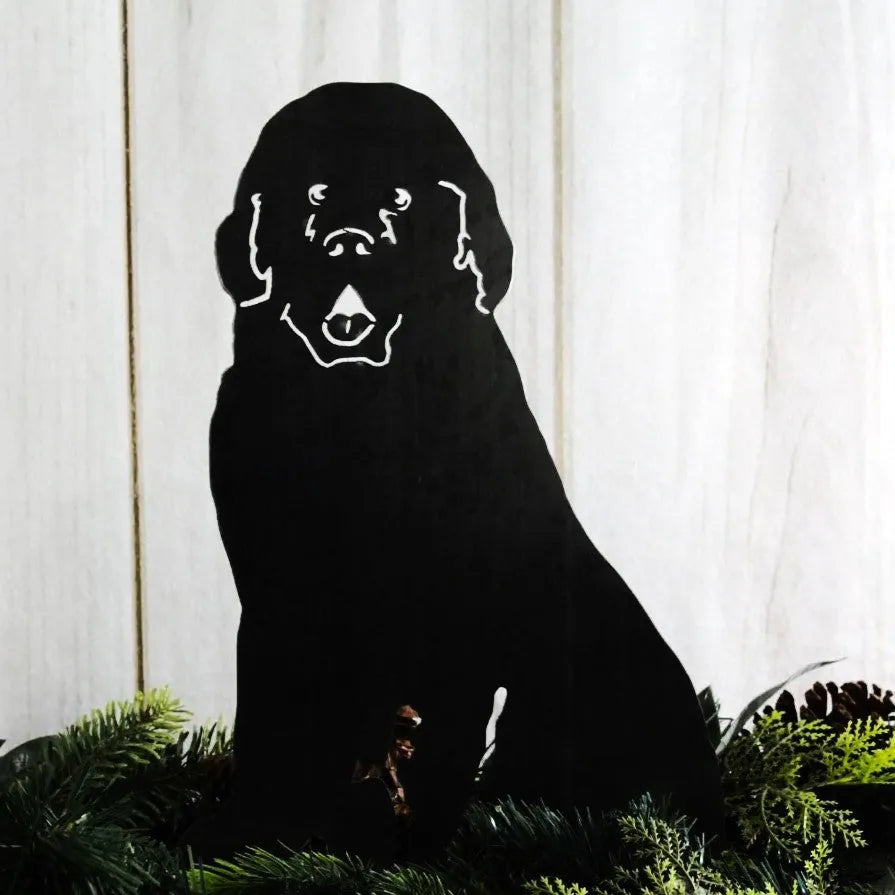 Black Newfoundland dog silhouette made of metal, showcased against a light wooden backdrop with greenery.